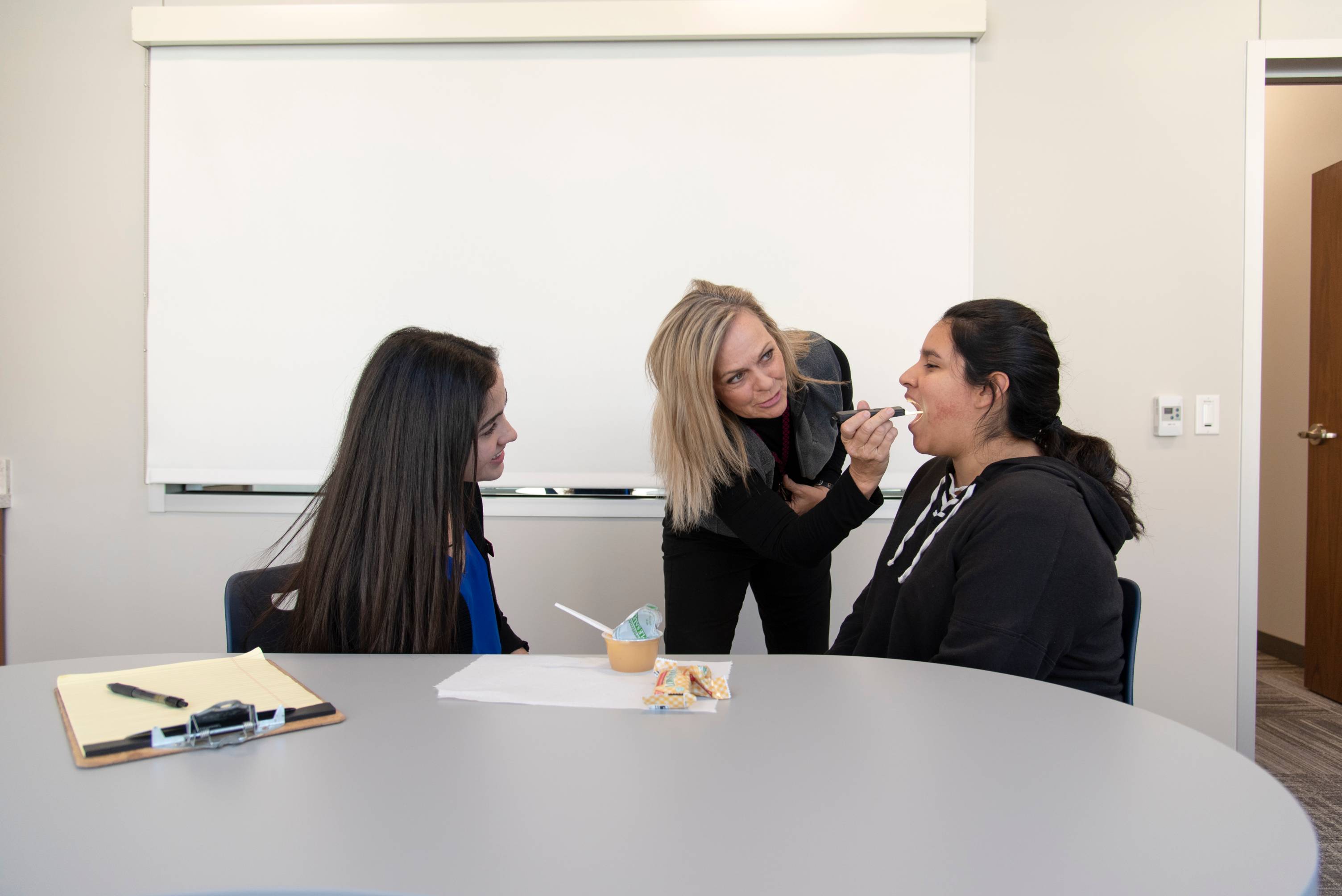 Student Clinicians examining patient's throat.