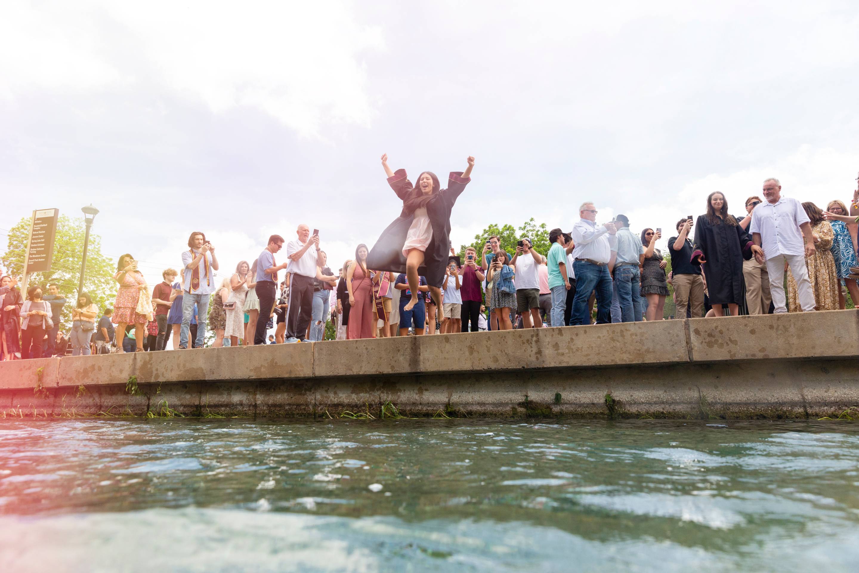 student leaping into San Marcos River