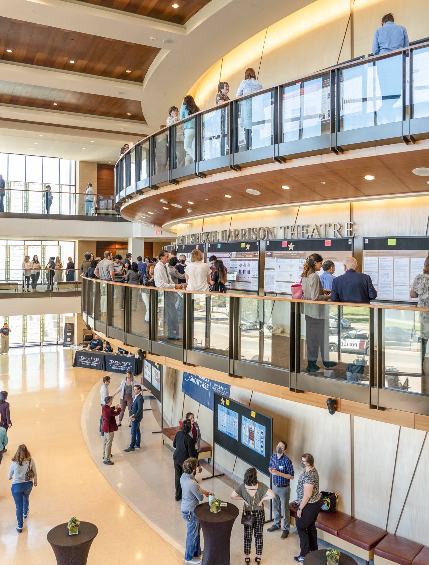 A photo of the second and third level balconies filles with research posters, presenters, and attendees.