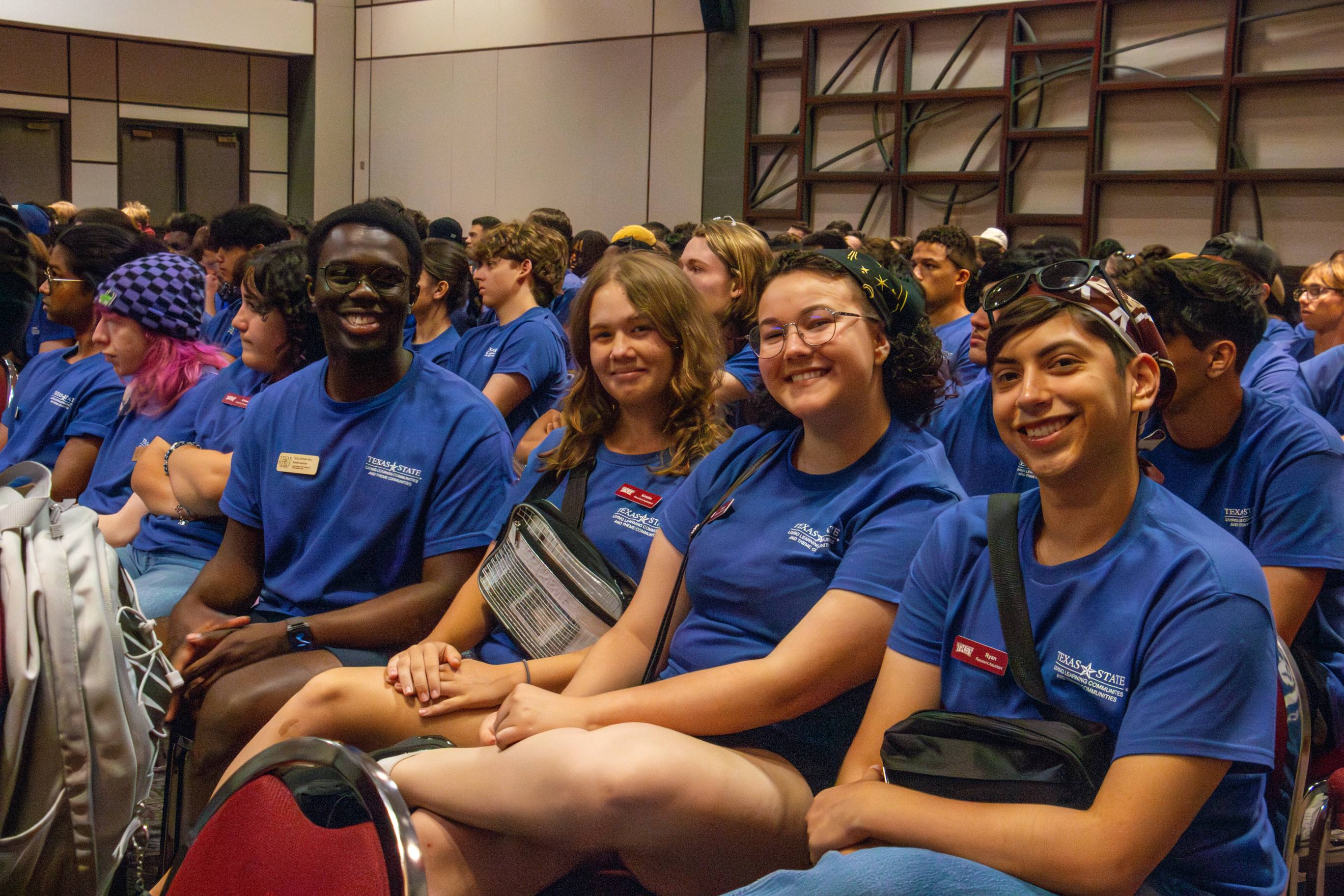 students in matching shirts smiling in lbj student center ballrooom