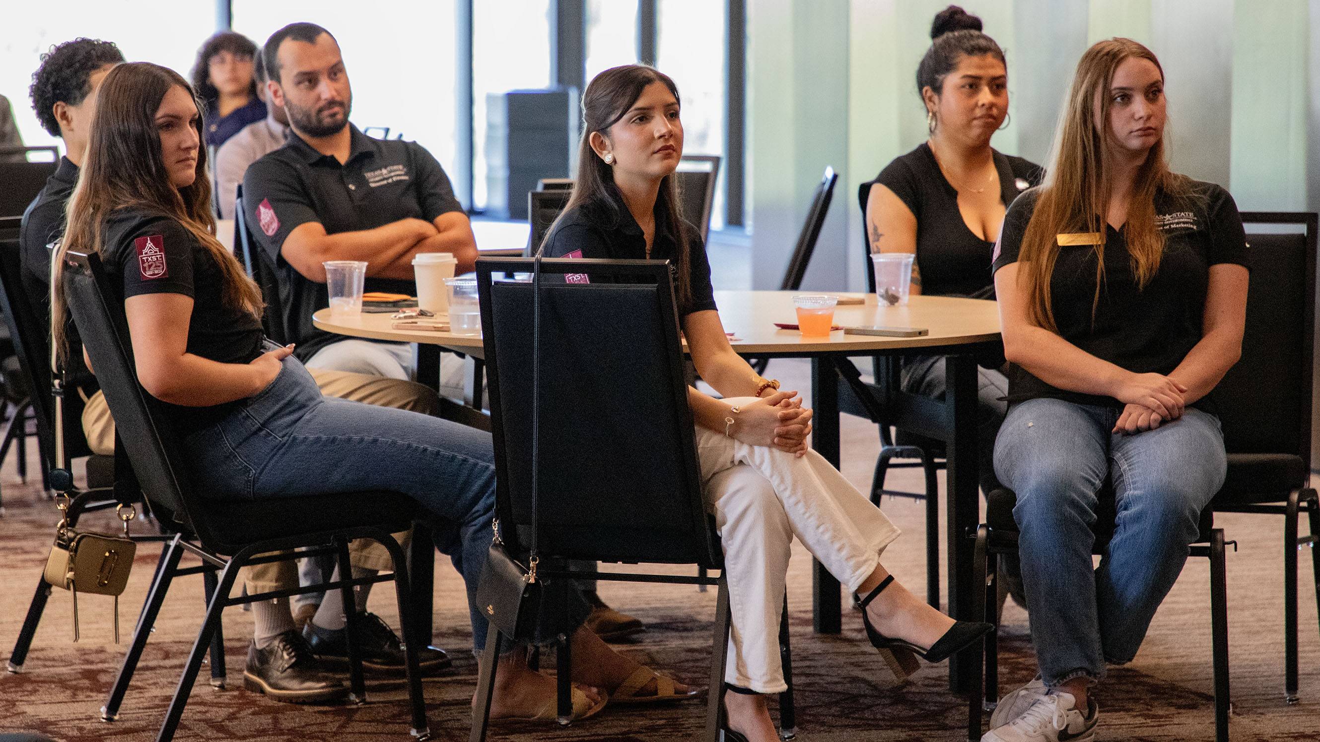 A group of students sit at a table and listen to speakers at the Elevate Employability Summit.