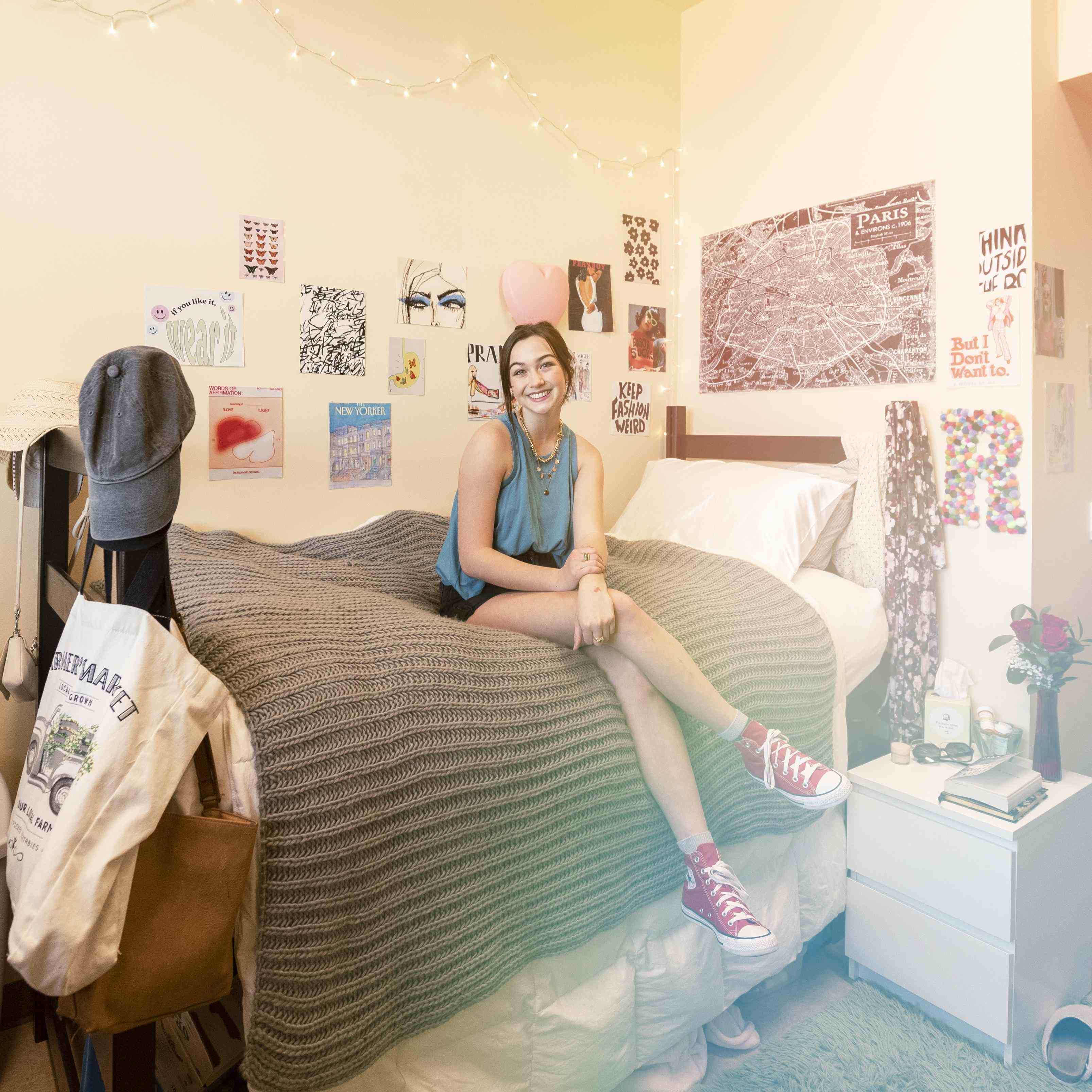 Smiling young woman sits on her dorm room bed.