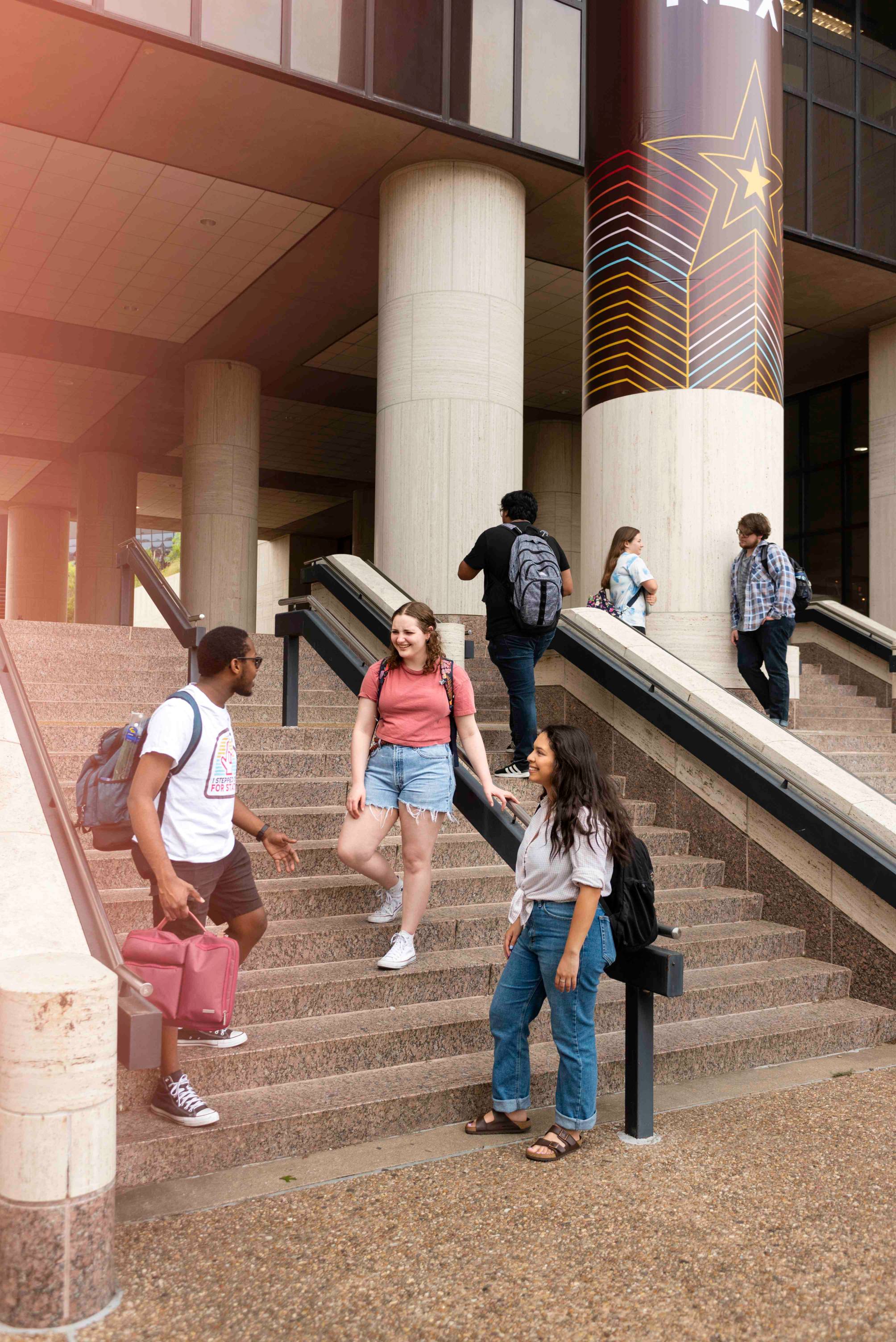 Three students pause to talk on a flight of steps.