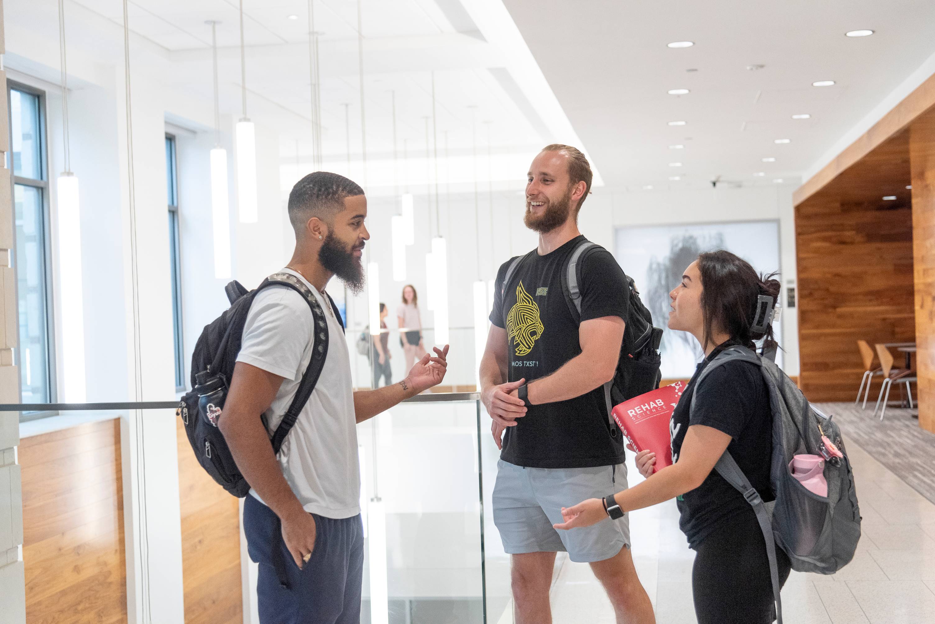 three students chatting while standing outside of class