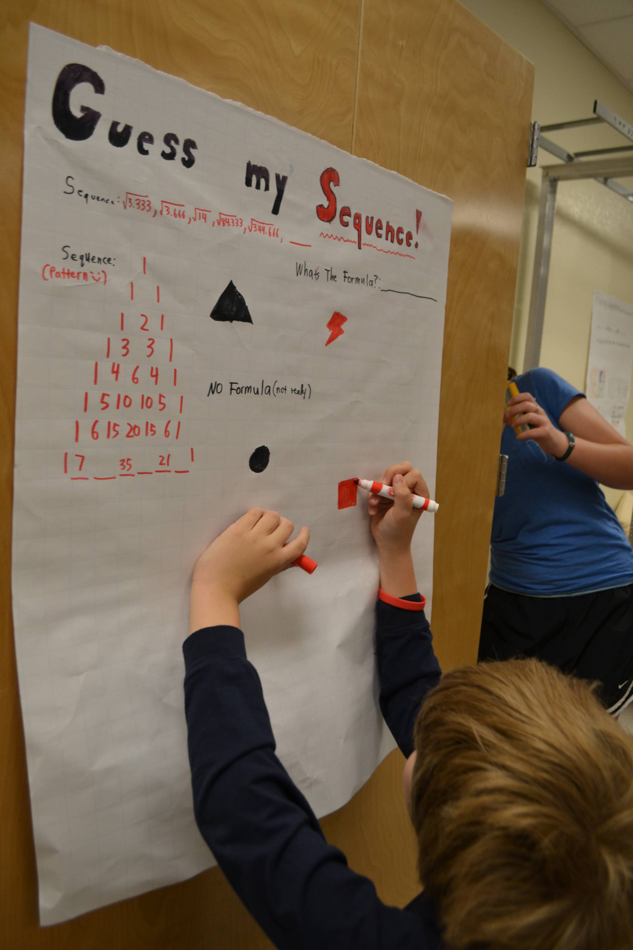 Student making a poster titled Guess My Sequence.