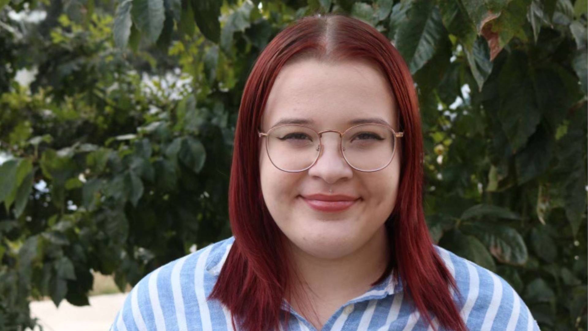 woman with red hair and glasses, trees