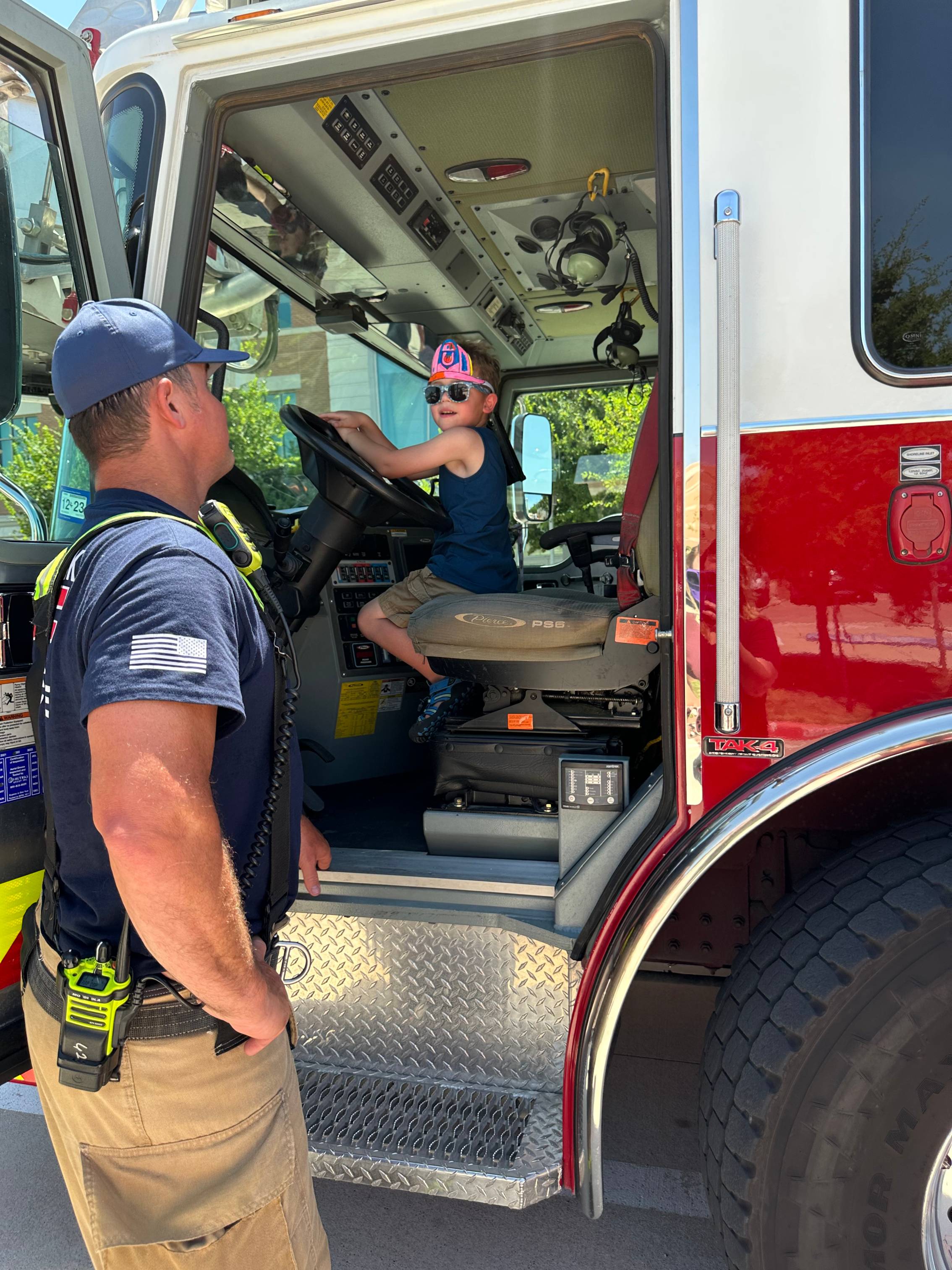 Young patient riding a firetruck during the firefighters visit to our campus.