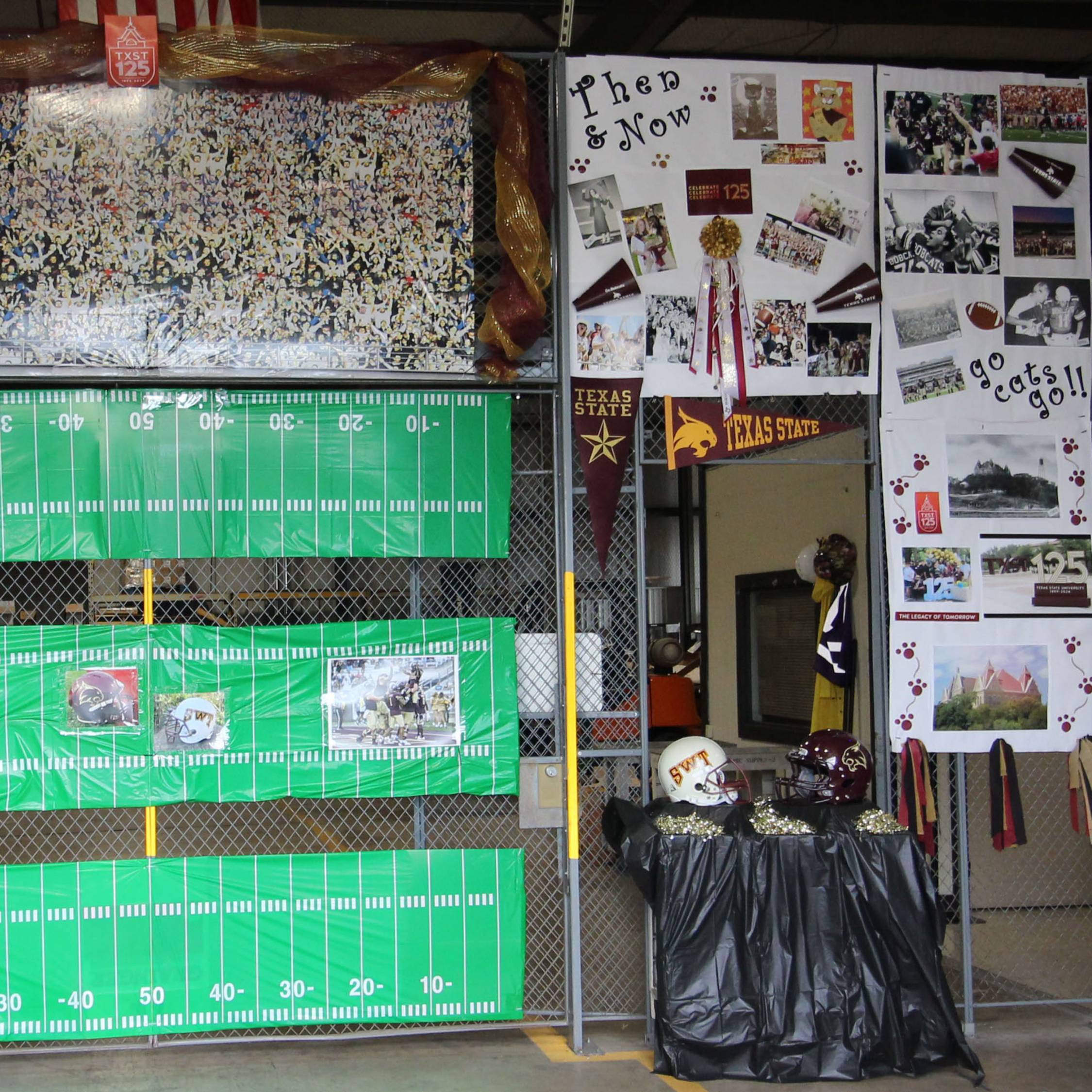 Warehouse decorated with a made up football field along with posters with past and present pictures of TXST.