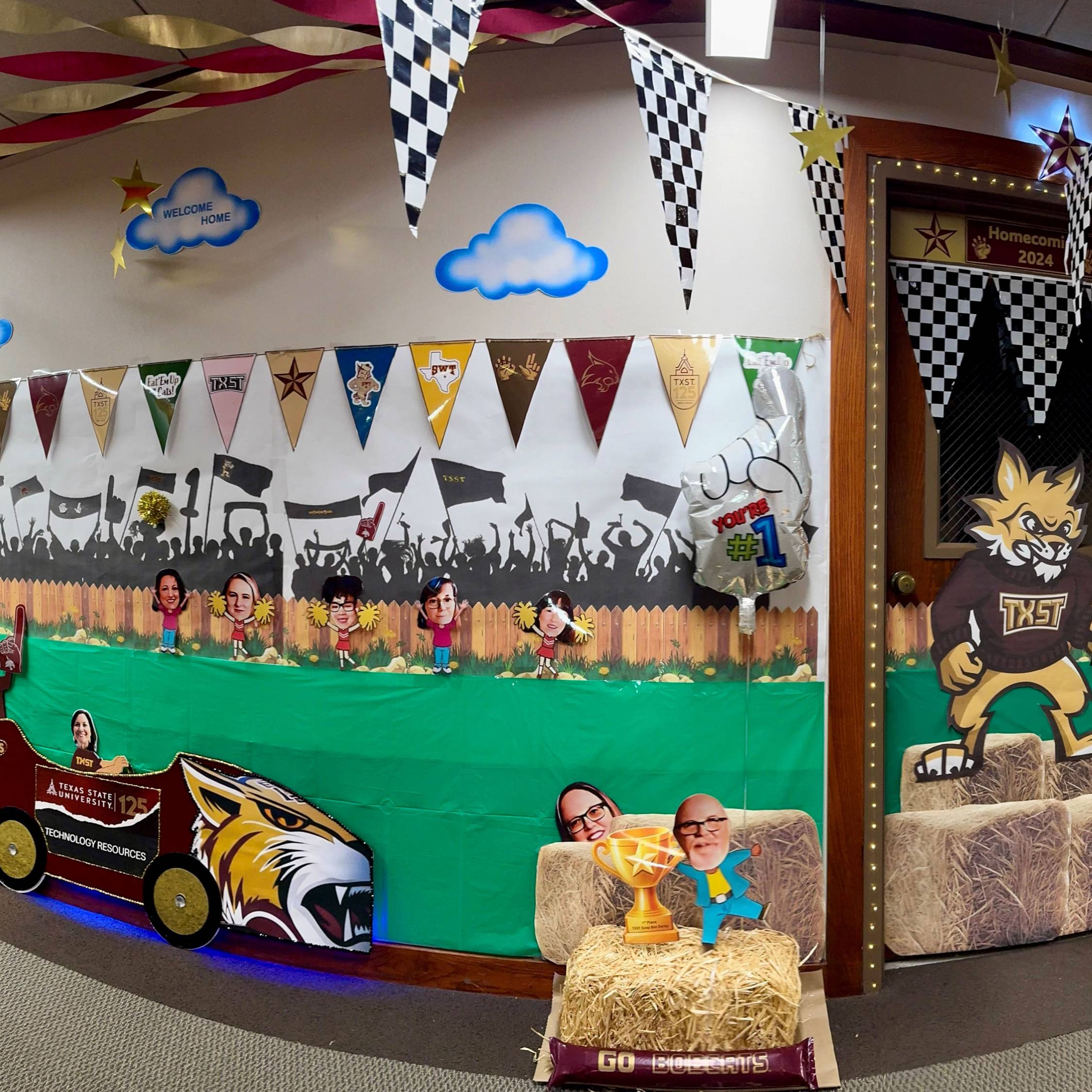 Hallway decorated as the Homecoming tradition Soap Box Derby. With images of Boko on a car along hay piles.