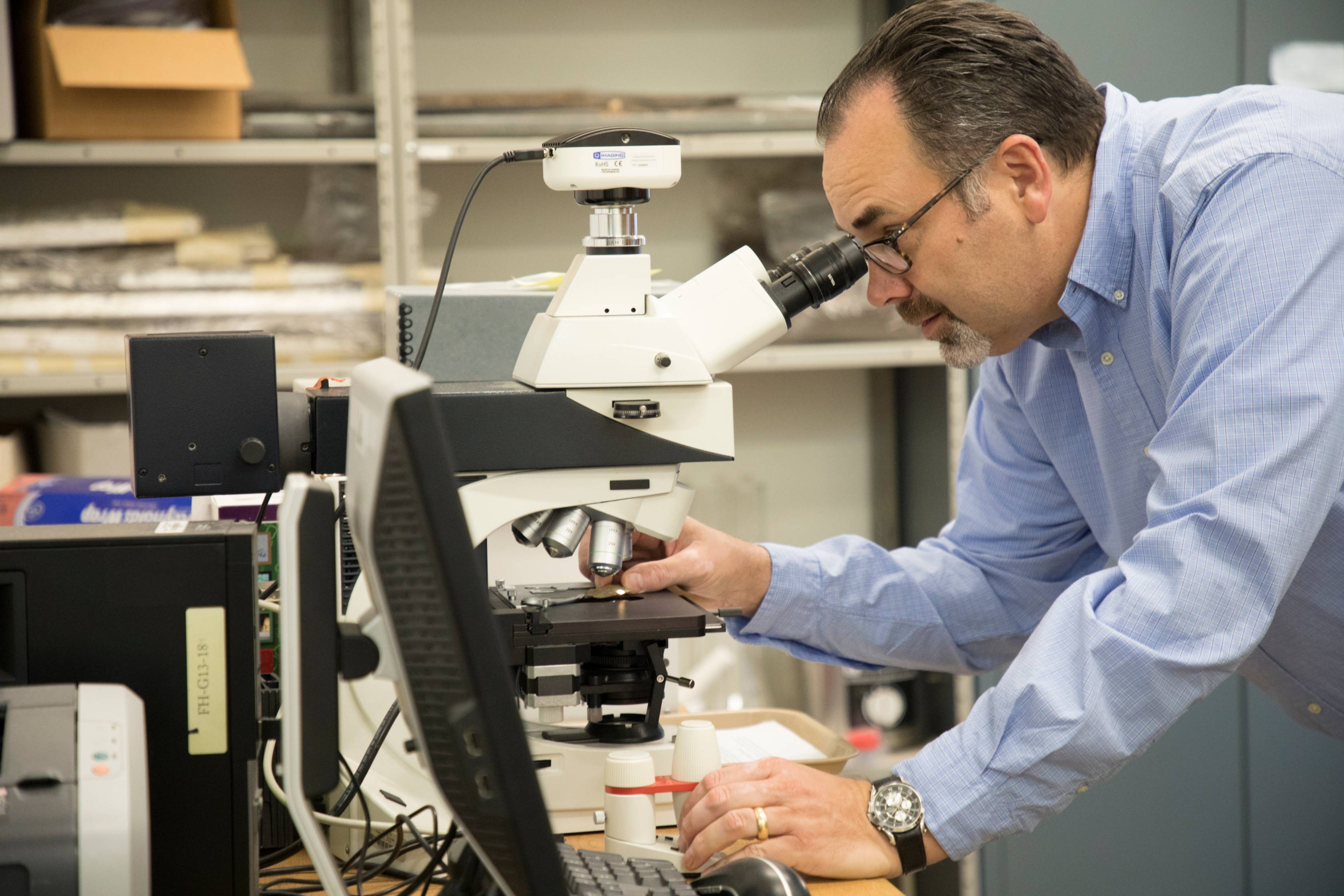 Professor Todd Ahlman looks at microscope