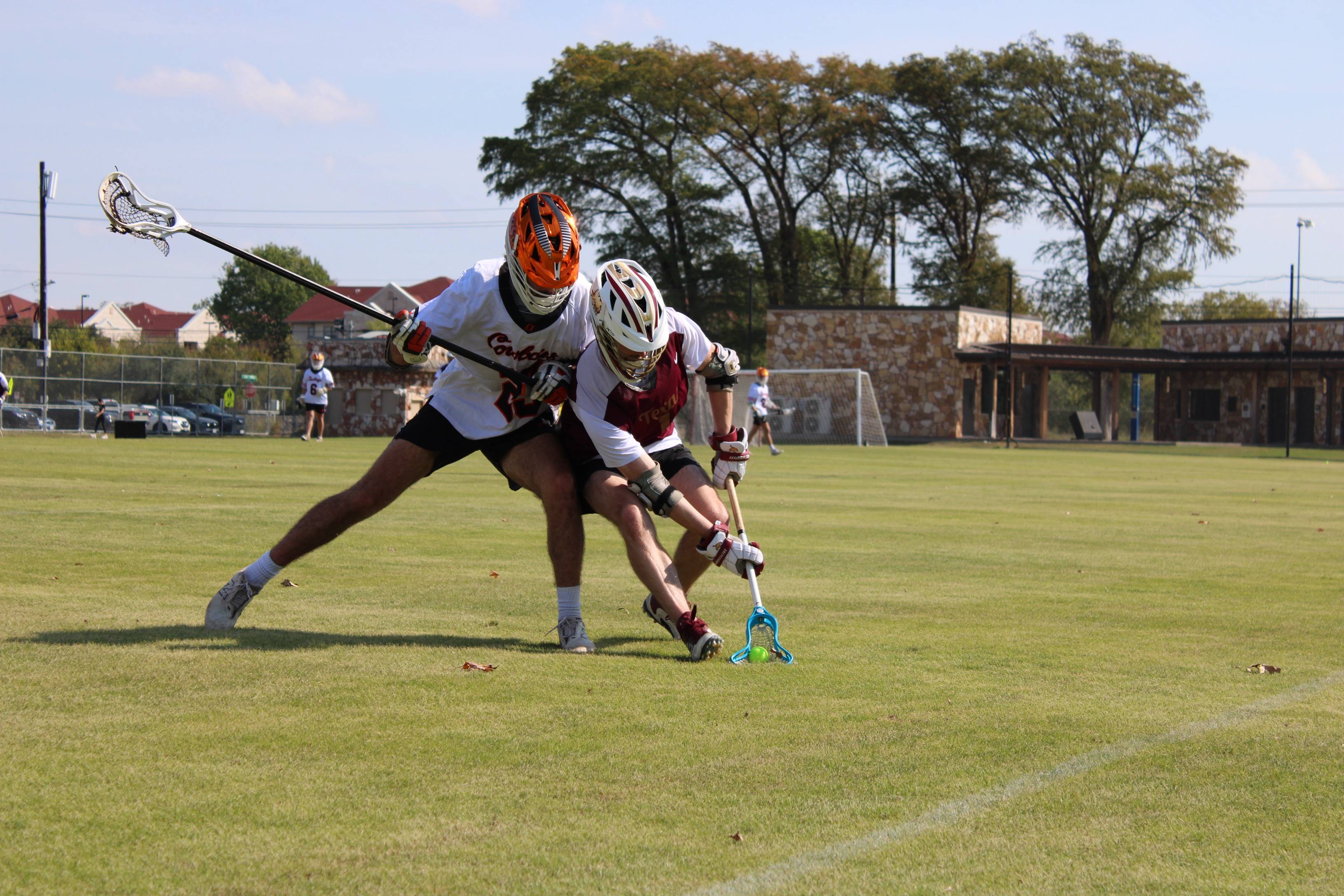 Men's Lacrosse sport club member crouching for a lacrosse ball while being defended