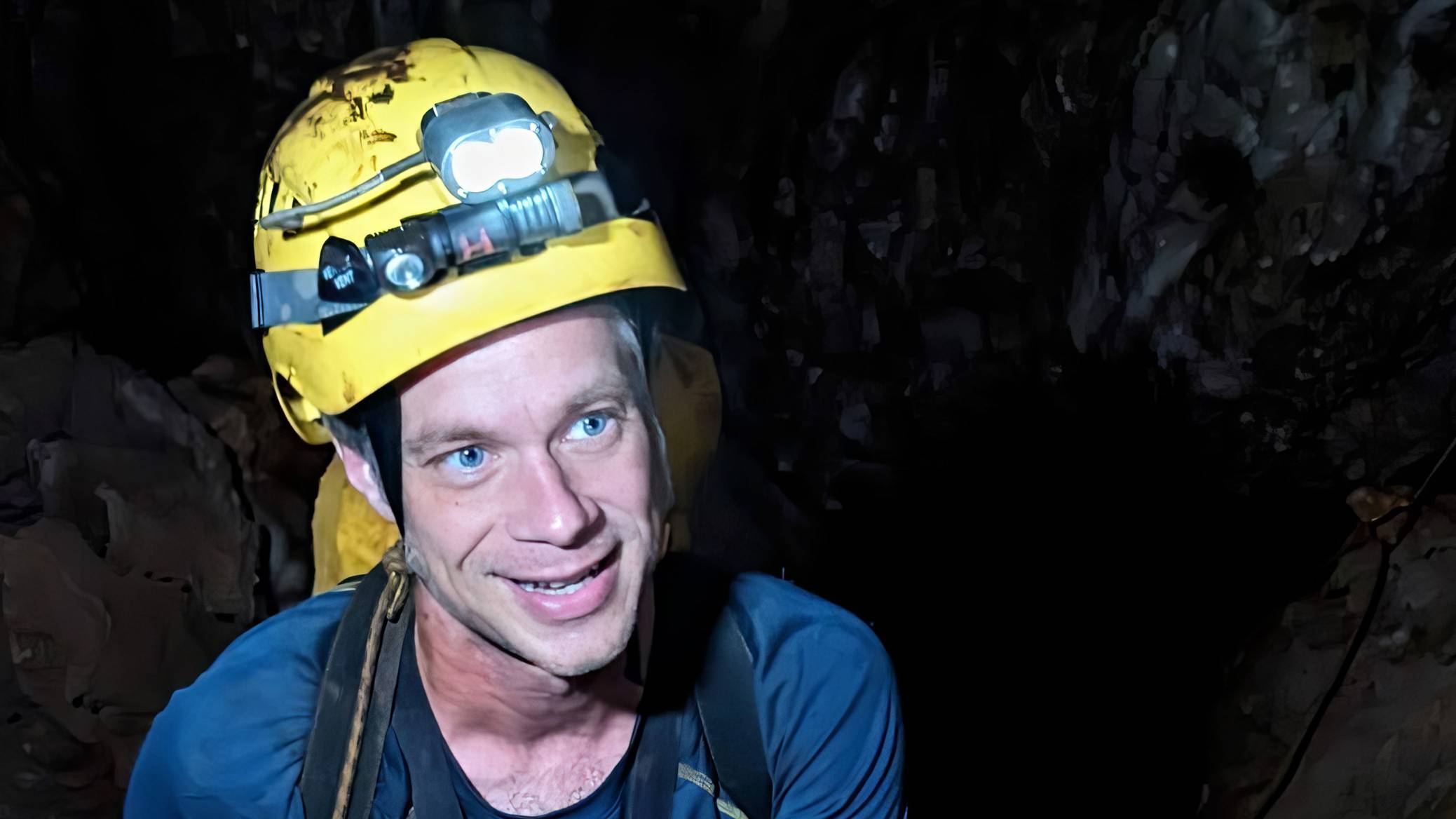 Ben Hutchins ropes down into a cave wearing a hardhat.