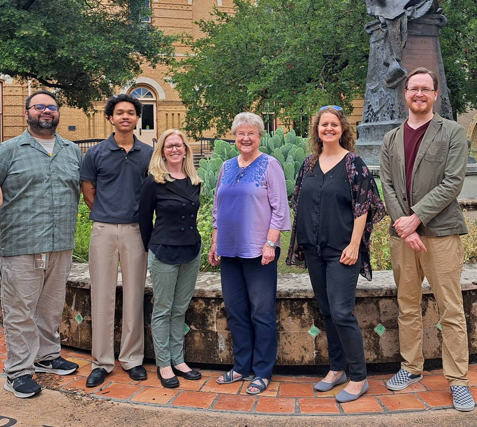 Staff members from Texas State University's University Advising Center pose for a picture in front of Old Main.