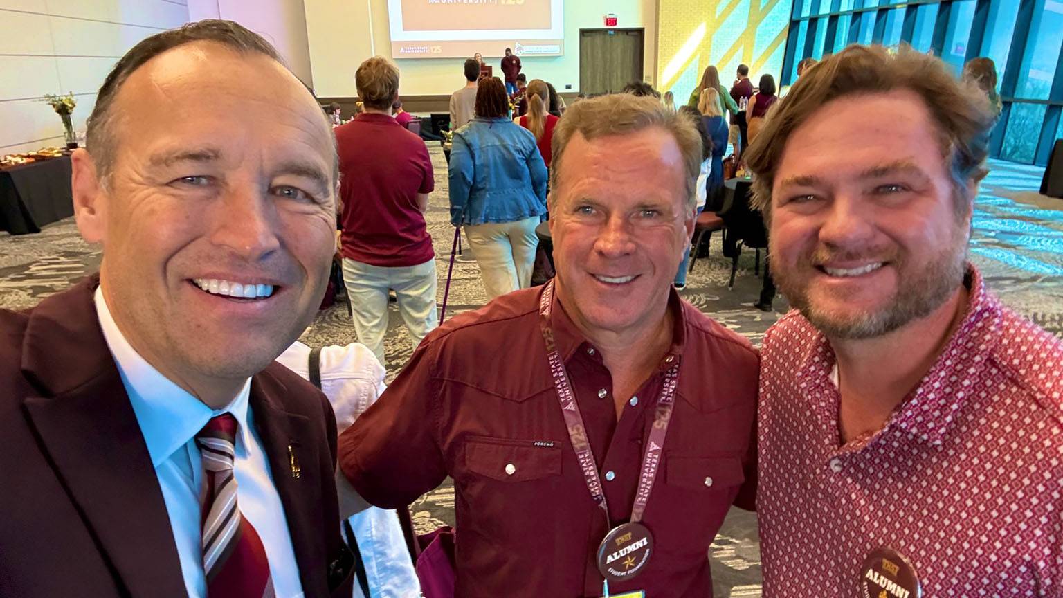 President Kelly Damphouse (left) poses for a picture with two TXST alums.