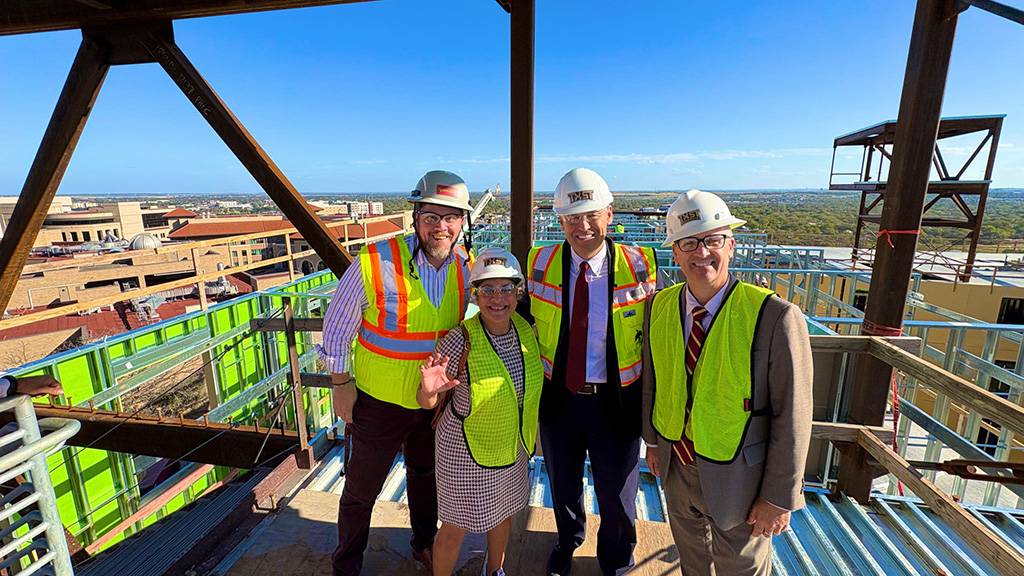 President Kelly Damphousse (second right) poses for a photo with TXST leadership memebrs on top of the new residence hall.