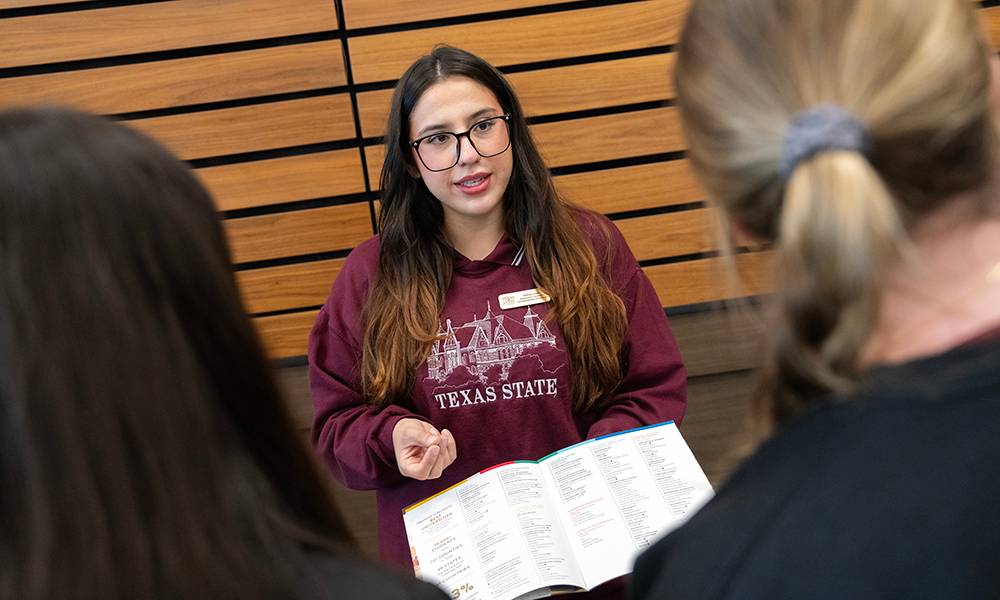 An admissions counselor speaking with porspective students at a college fair