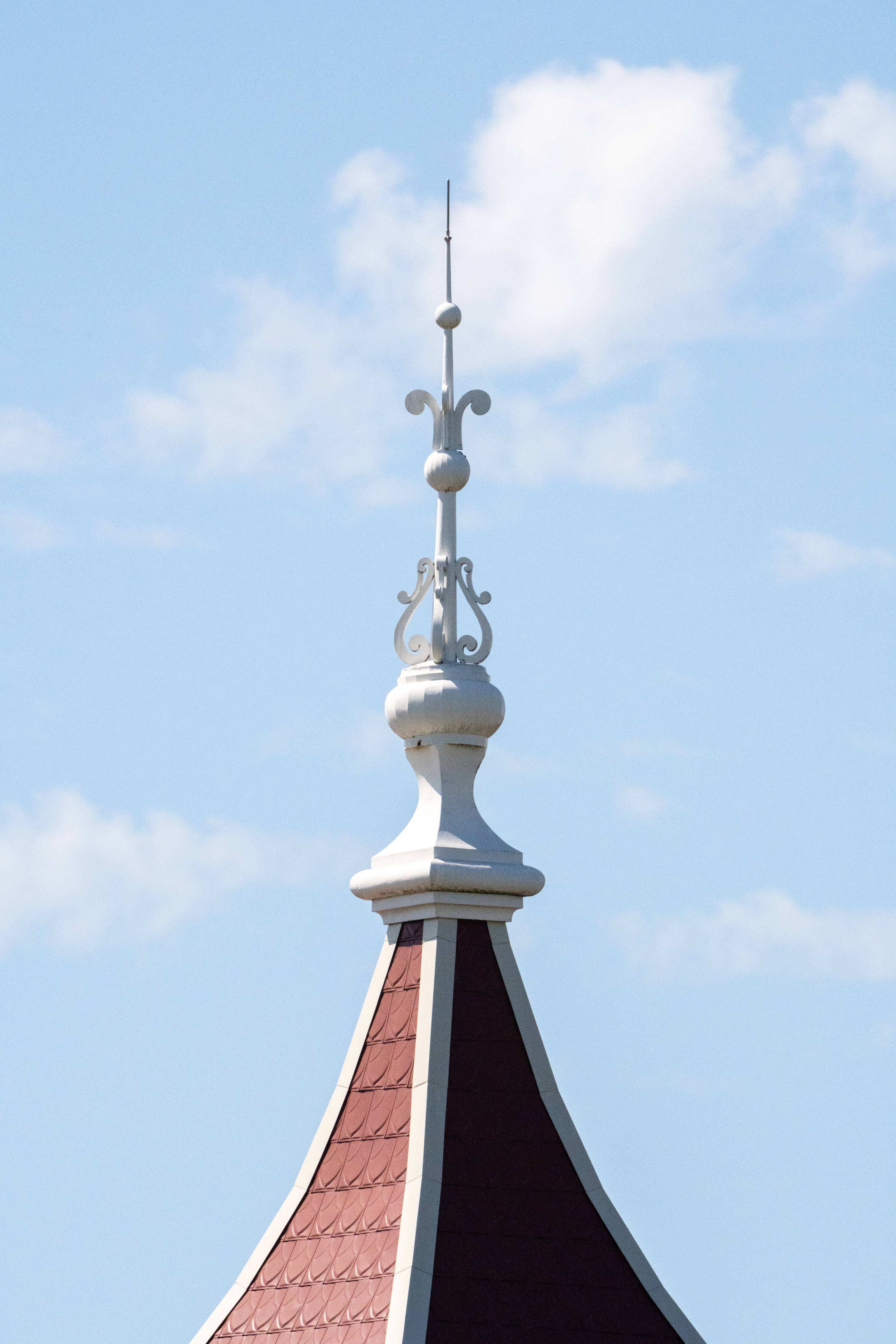 Ornate metal spire on top of pointed red roof.