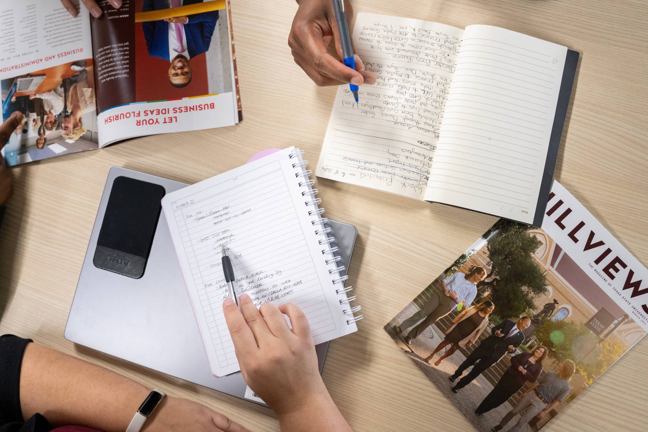 Aerial shot or hands on a table working writing in a notebook and hovering near a laptop
