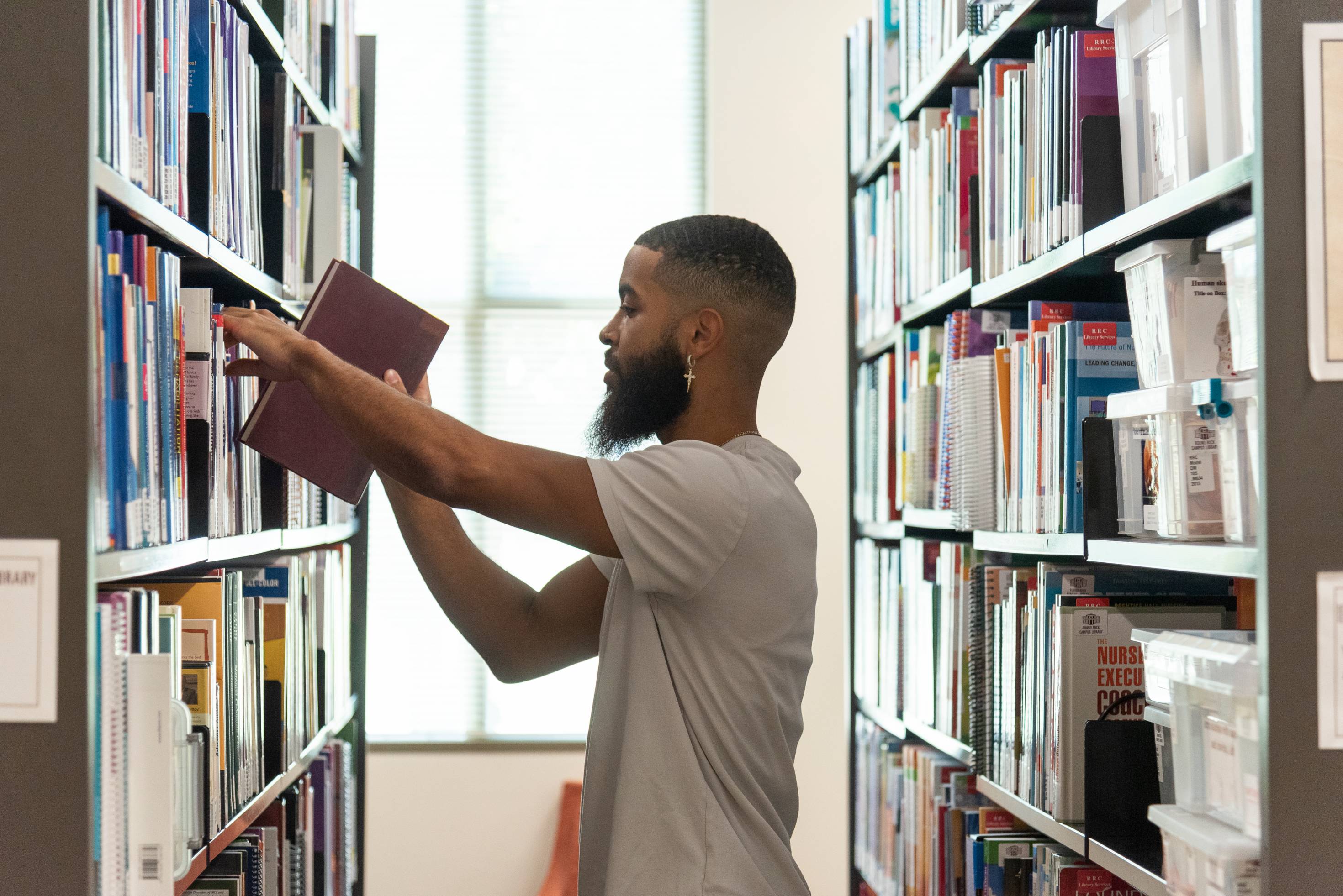 Man taking a book from a book shelf