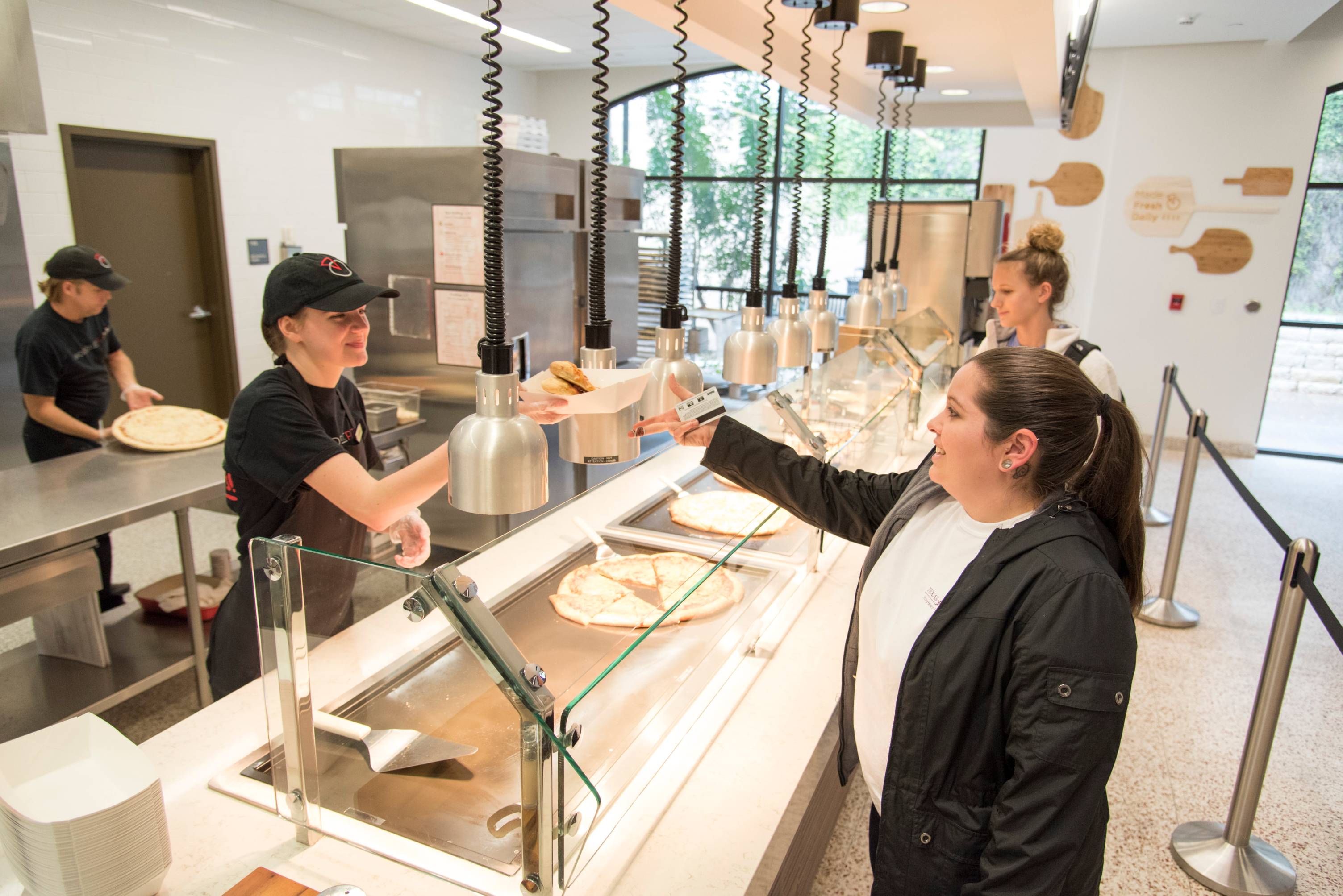 Dining Hall employee hands female student a plate of food. 