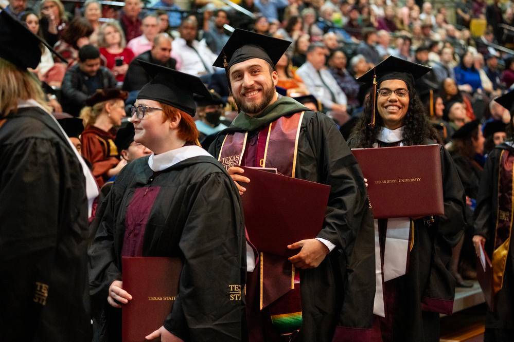 Two students holding diplomas at gradation