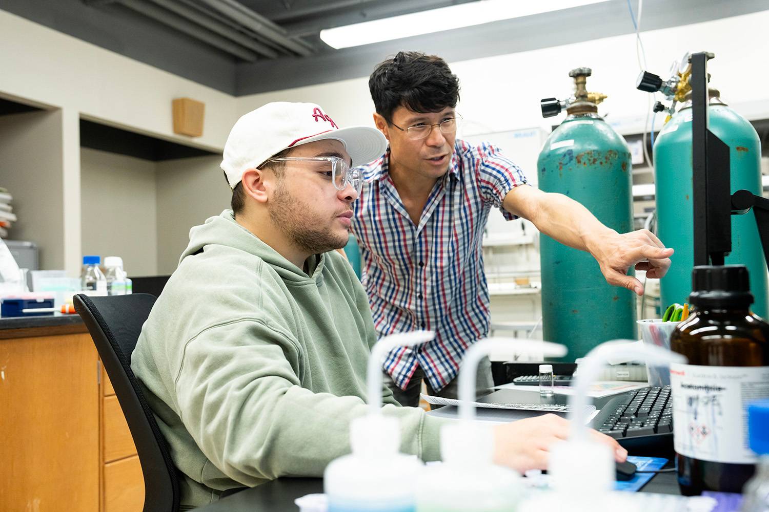 A Texas State teacher helps students with their assignments during a graduate chemistry lab session. 