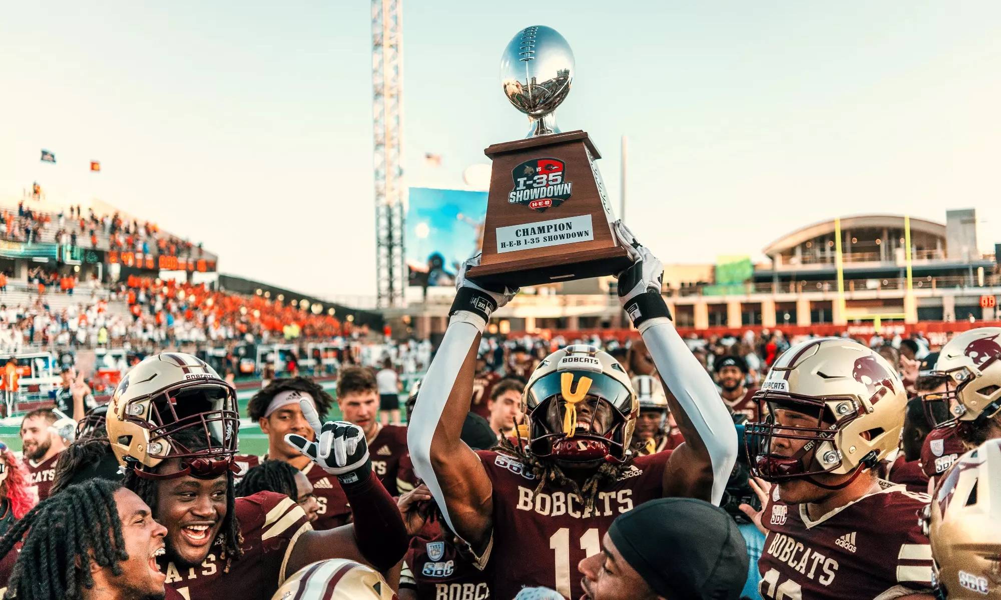 Defensive end Deven Wright lifts the I-35 Showdown trophy following the Bobcat Victory.