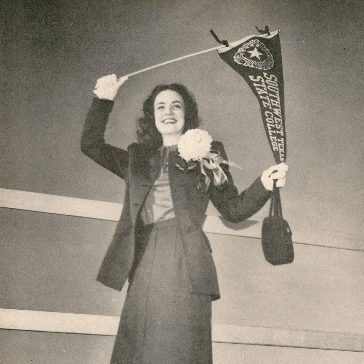 A young woman holds up a pennant reading 'Southwest Texas State College.'