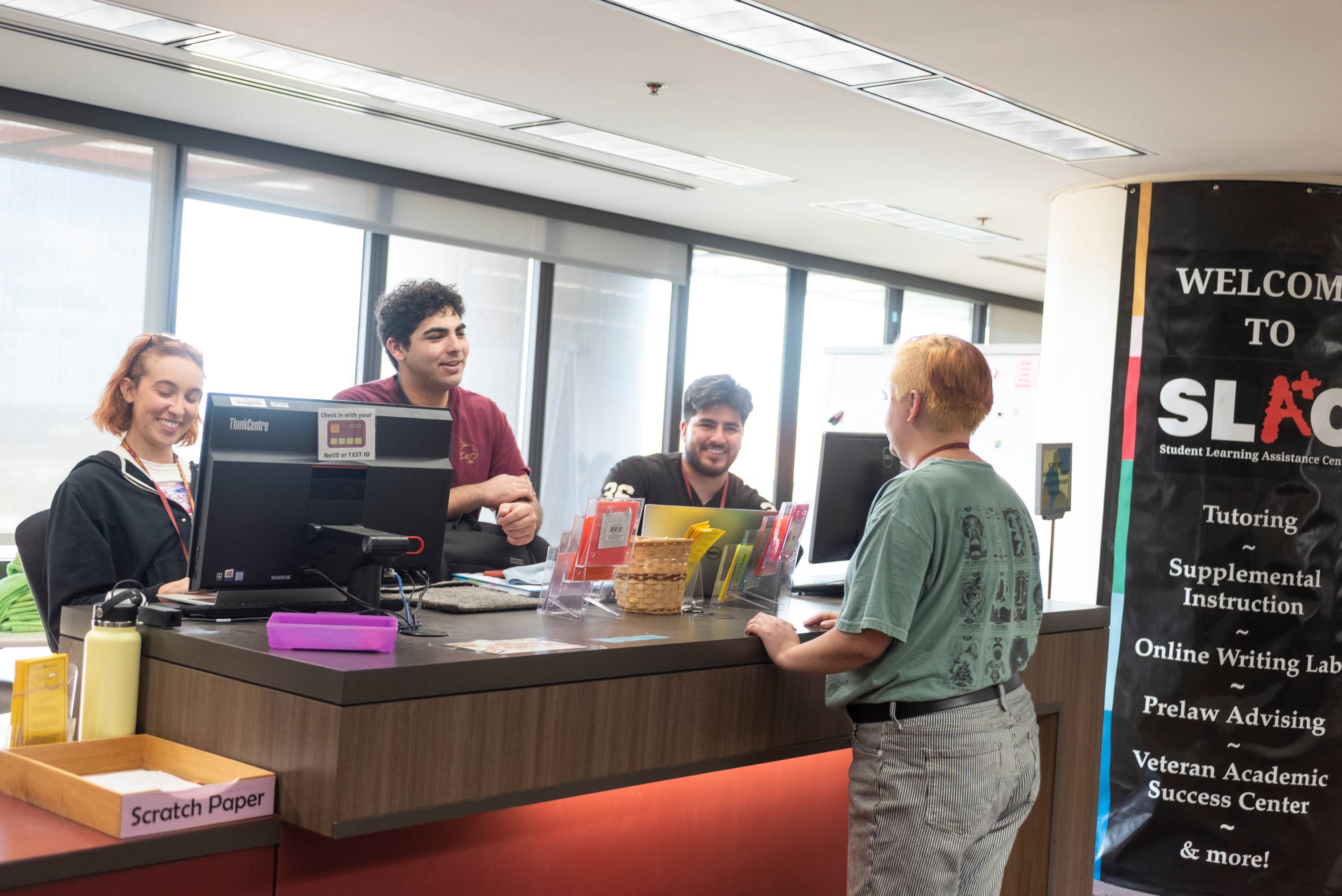 A student at the welcome desk of SLAC being greeted by three staff members