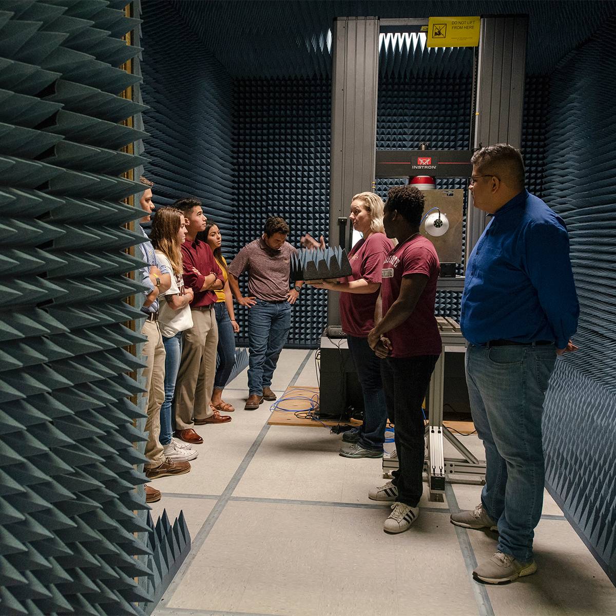 Students in a Texas State Biology lab huddle together, watching another student prepare samples for further research.