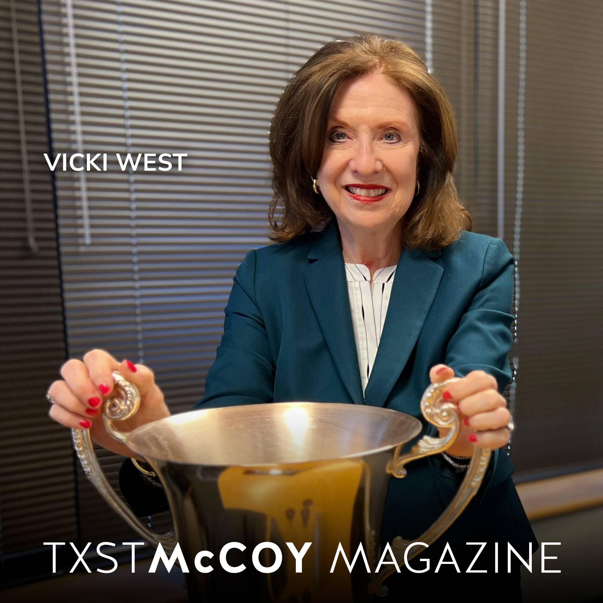 Vicki West in business attire holding onto a large trophy