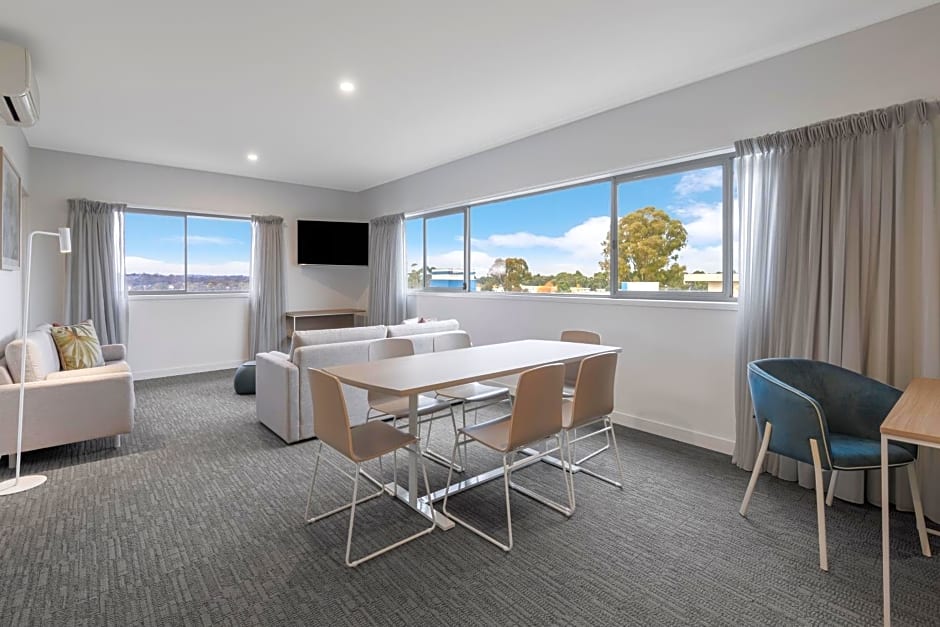 view of libing room space with TV, couch, dining table with large window overlooking outside.