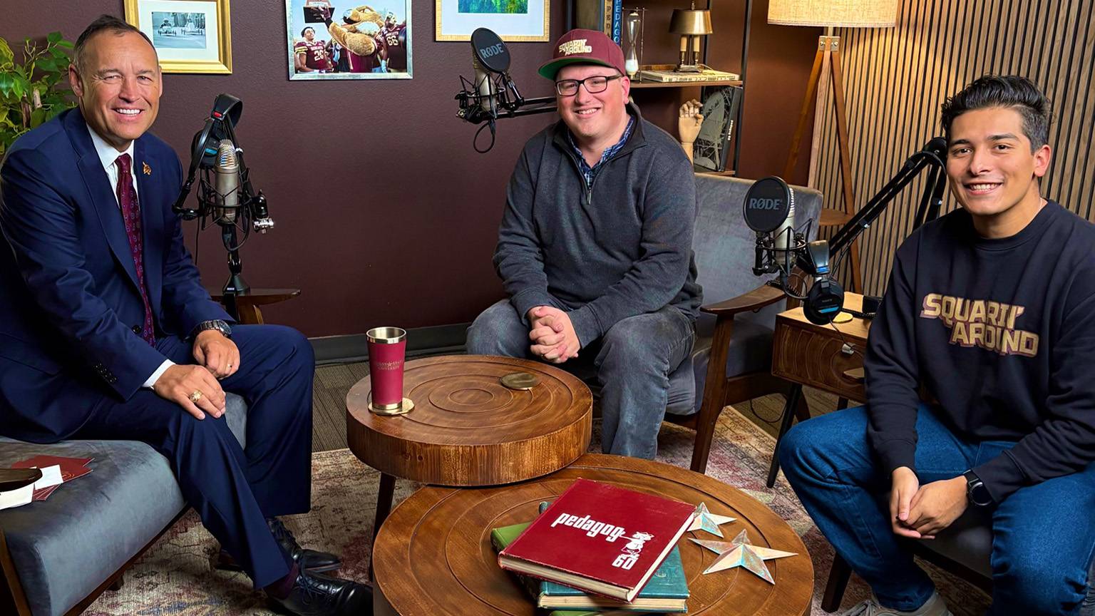 President Kelly Damphousse (left) poses for a photo in the podcast studio with the Squarin' Around podcast hosts.