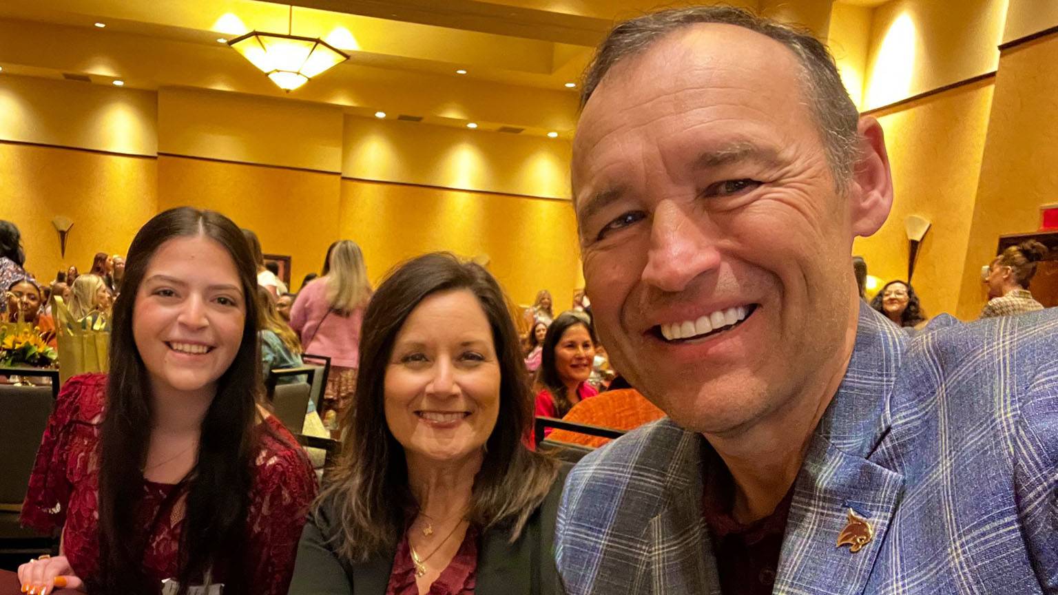 A student poses for a photo with First Lady Beth Damphousse (middle) and President Kelly Damphousse (right).