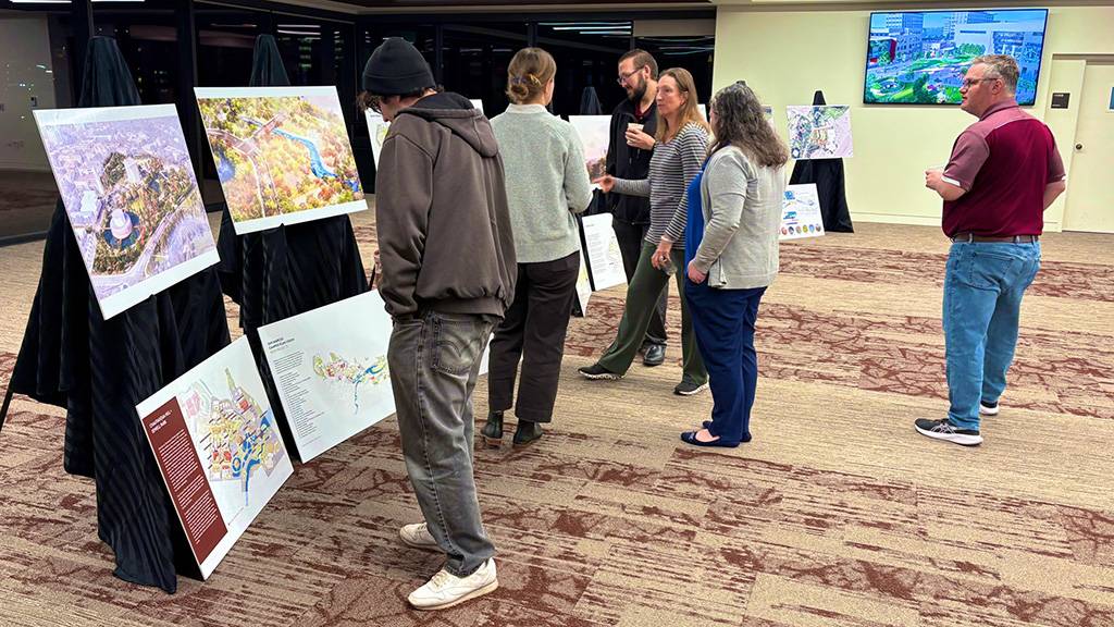 A group of TXST students and staff members look at Master Plan boards with planning materials attached to them.