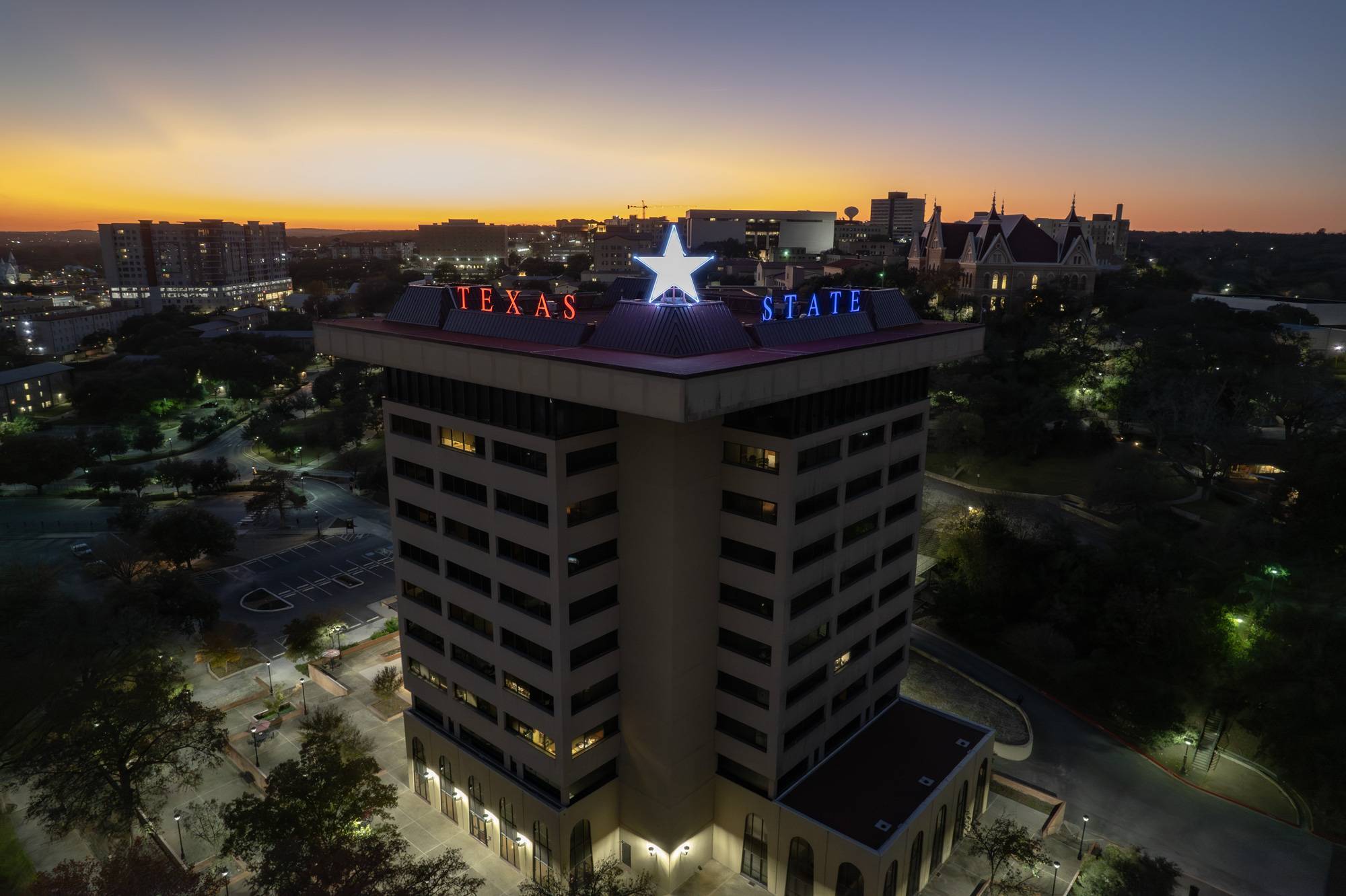 The Victory Star glows on top of the JC Kellam building. The words "texas state" and the star are in a red, white, and blue design. 