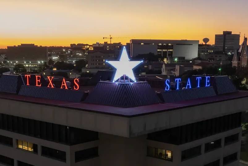 The Victory Star glows on top of the JC Kellam building. The words "texas state" and the star are in a red, white, and blue design. 