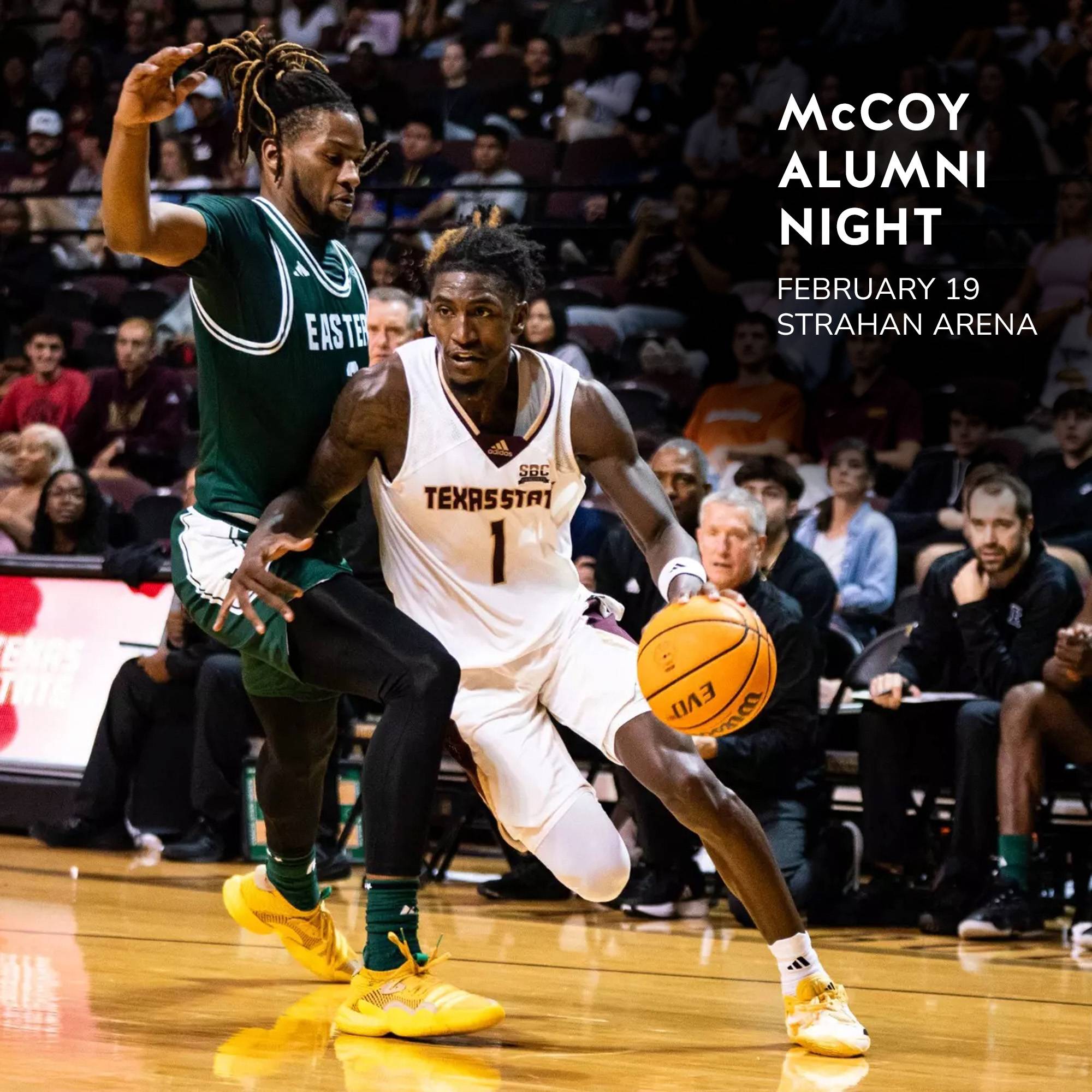 Texas State basketball player dribbles past Eastern Michigan player in front of large crowd