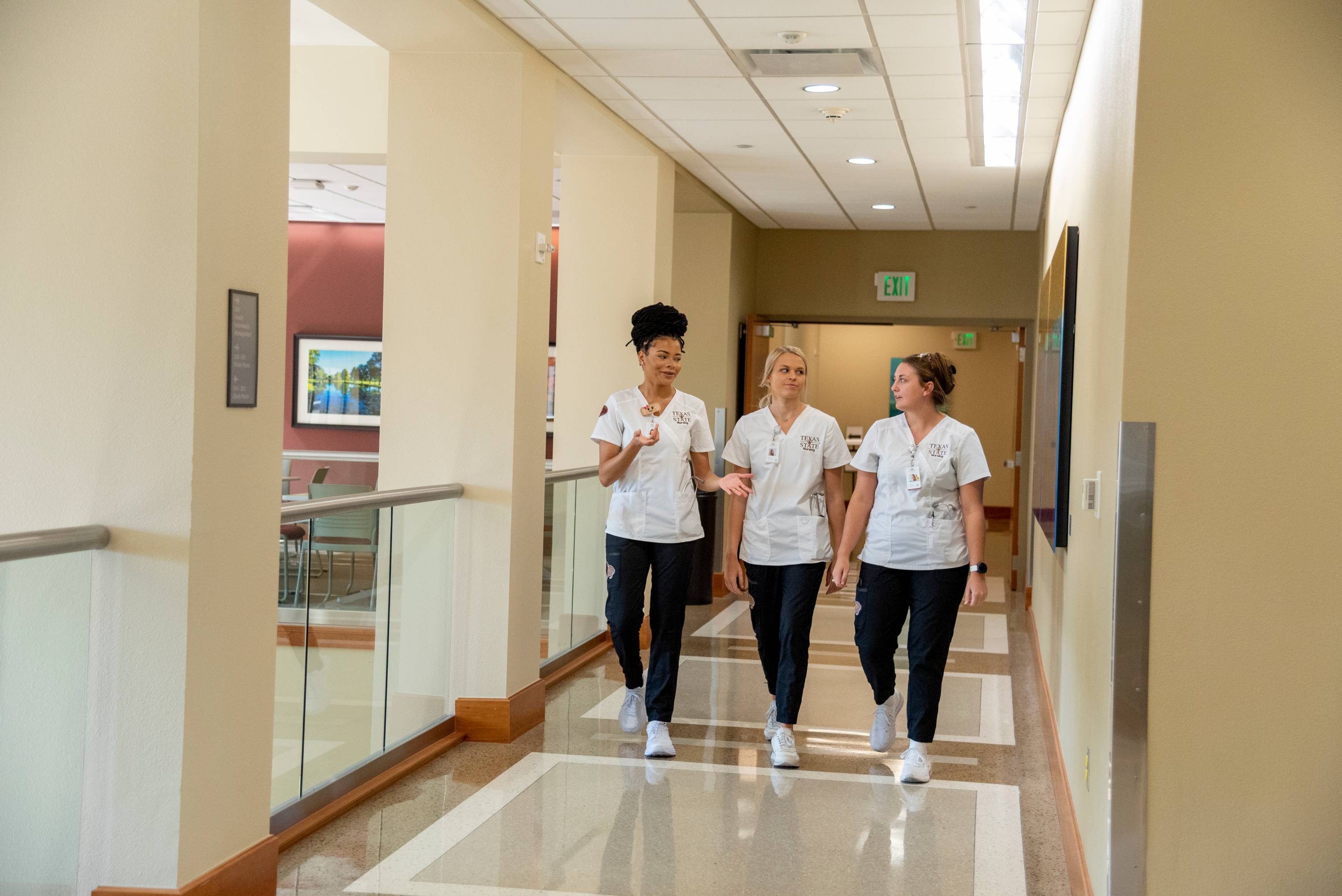 three female students in nursing scrubs walking on the round rock campus