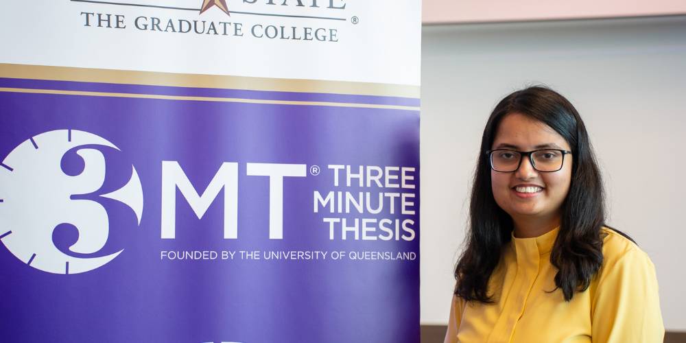 Maria Sultana standing next to a 3MT sign with her arms crossed