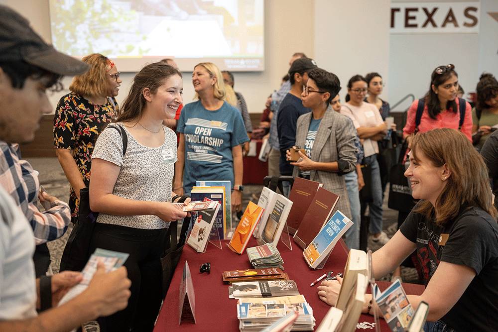 A prospective graduate student laughing while talking with a staff member from TXST