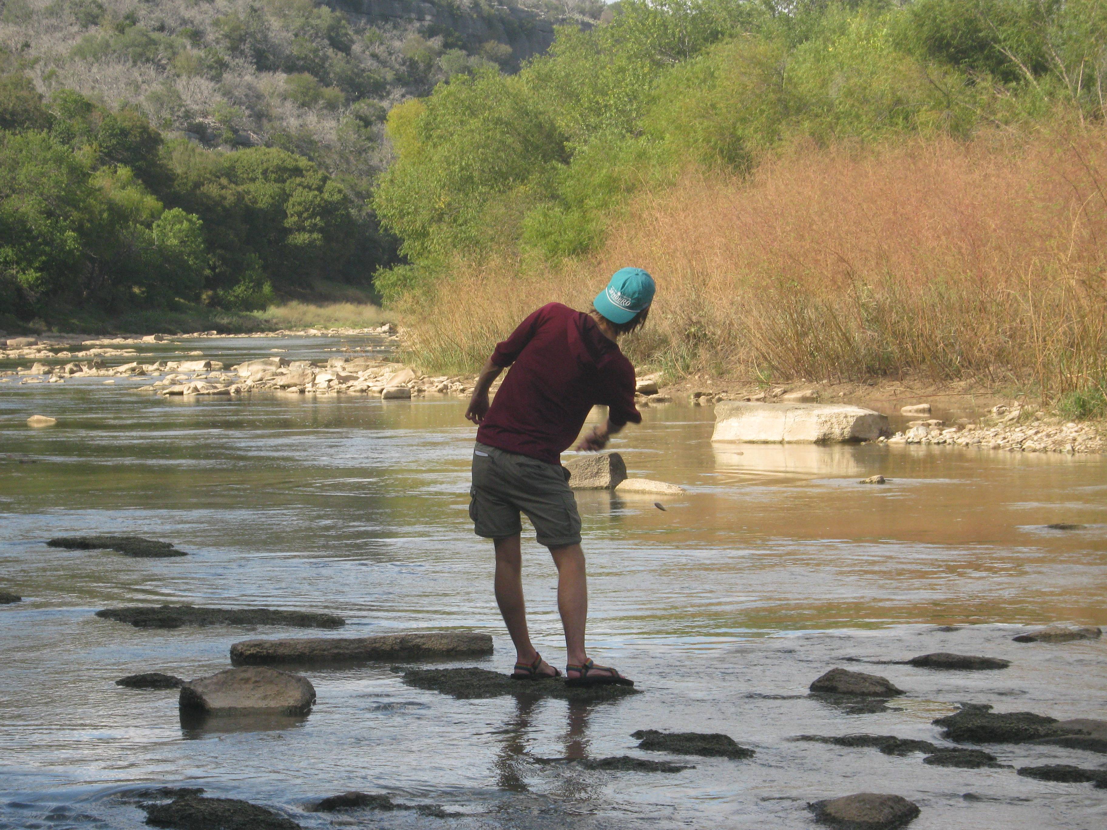 Student skipping rocks on a river