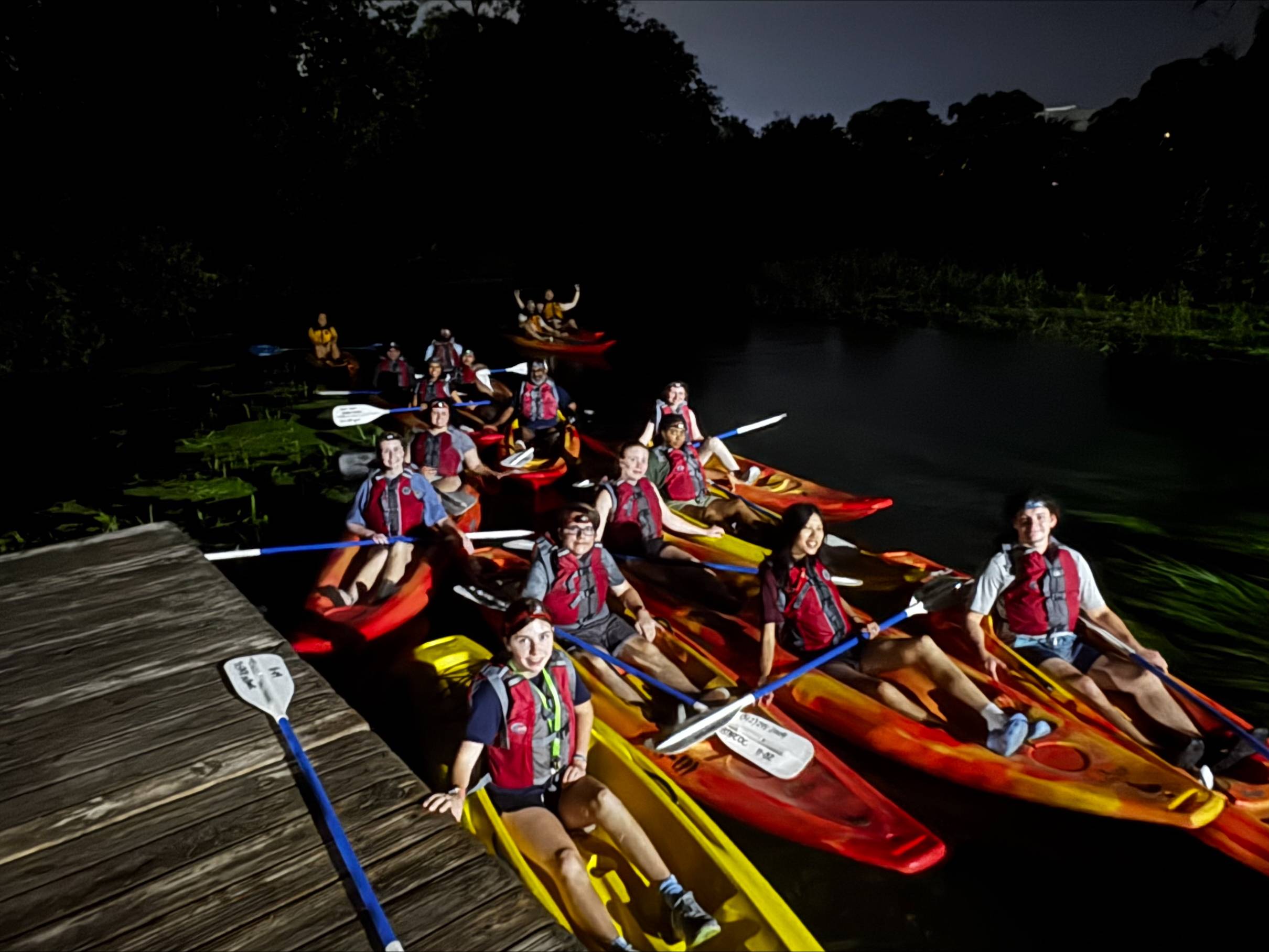 Students kayaking together at night