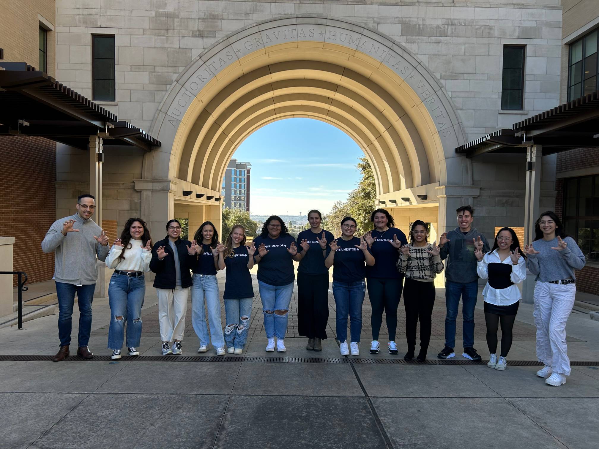 A group of Peer Mentors and Peer Mentoring staff under the THH arch.