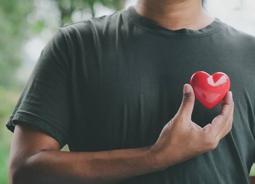 a person holding a 3D red heart over the left side of their chest