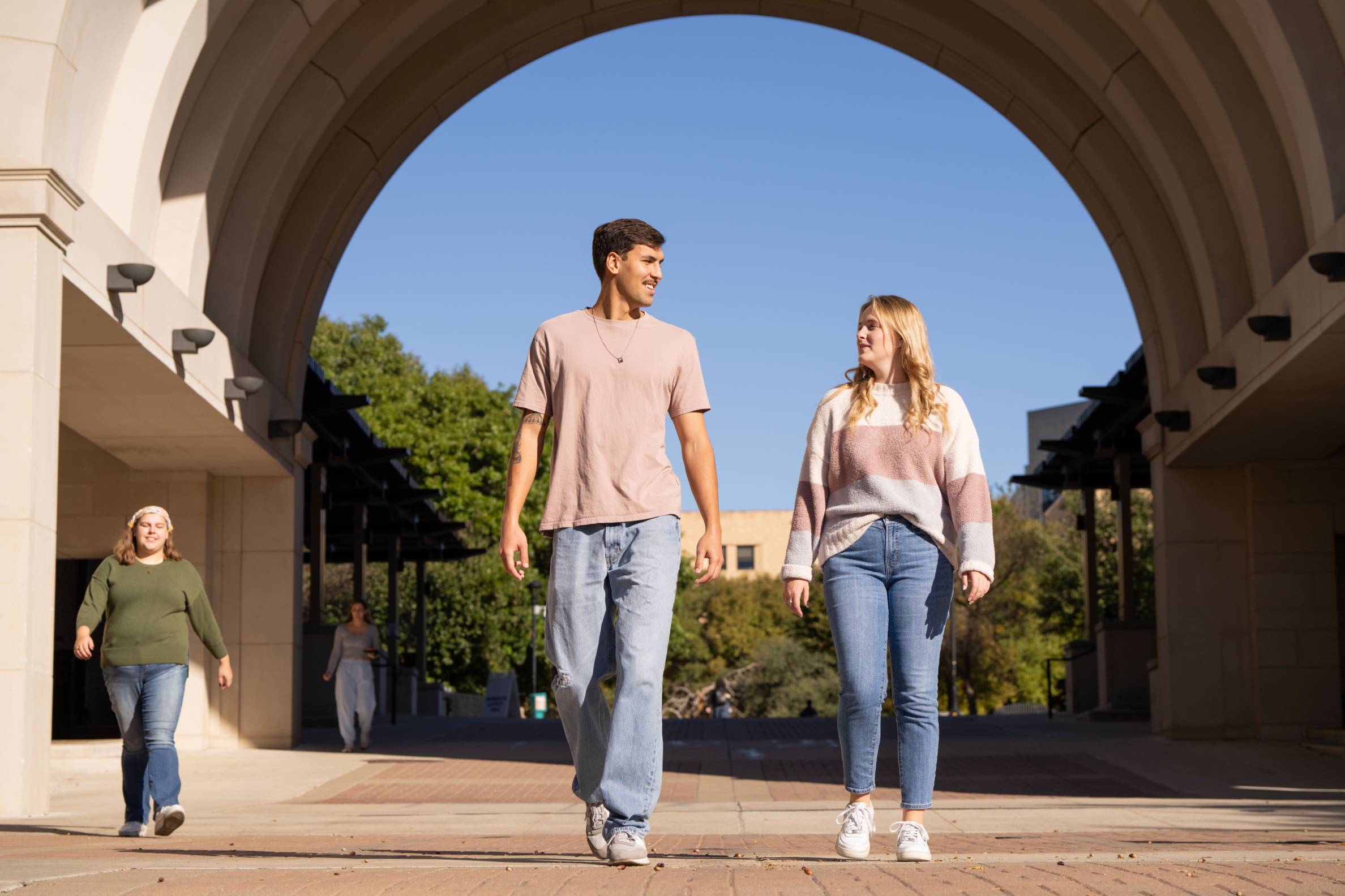 Two TXST Students Walking Under the THH Arch