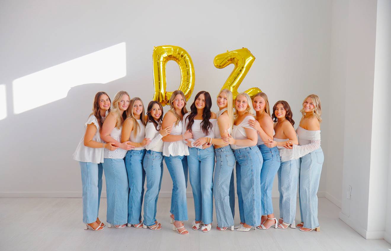 The executive board of Delta Zeta posing with gold "D" and "Z" balloons.