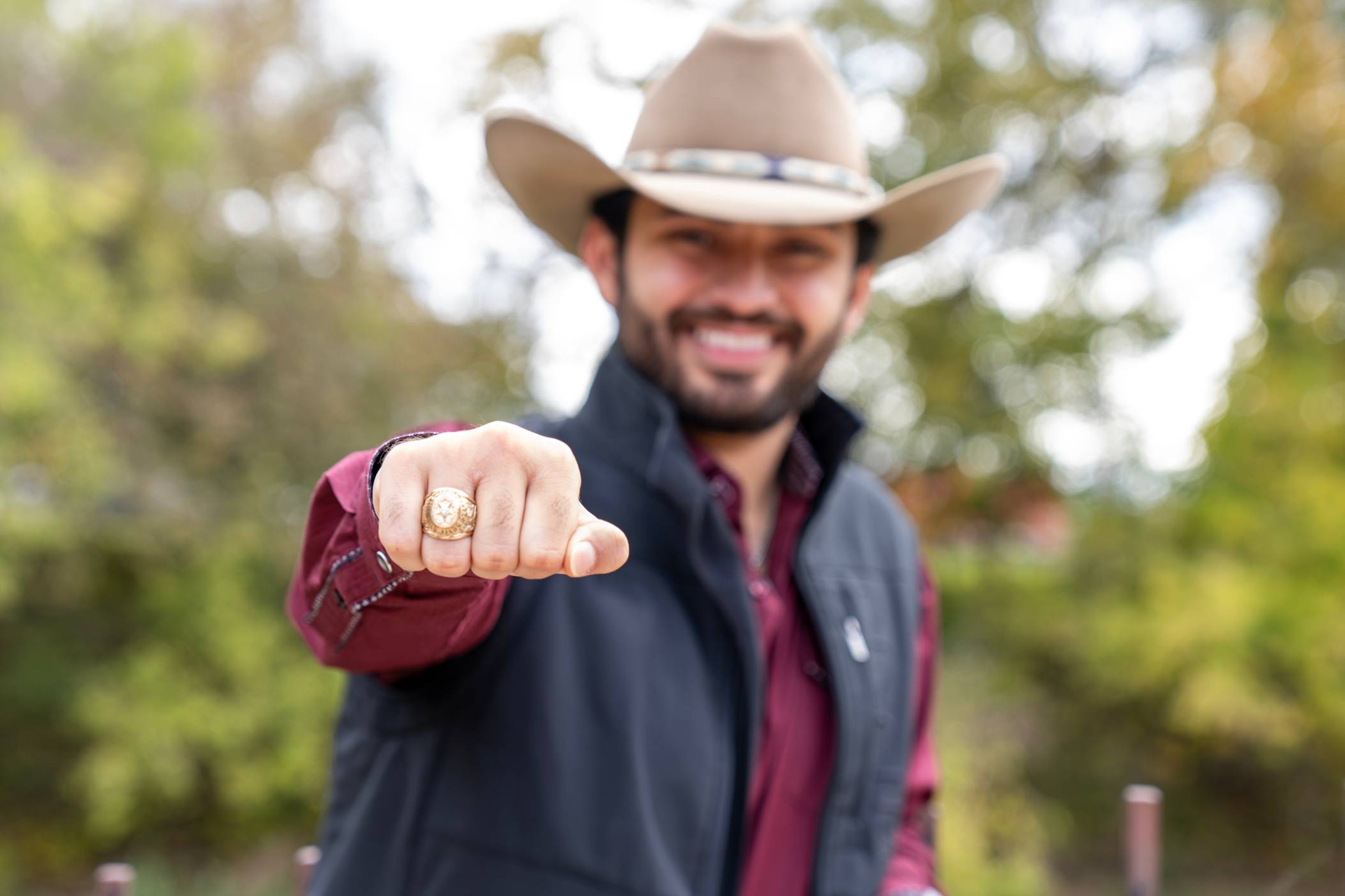 A young man proudly displays his TXST ring.