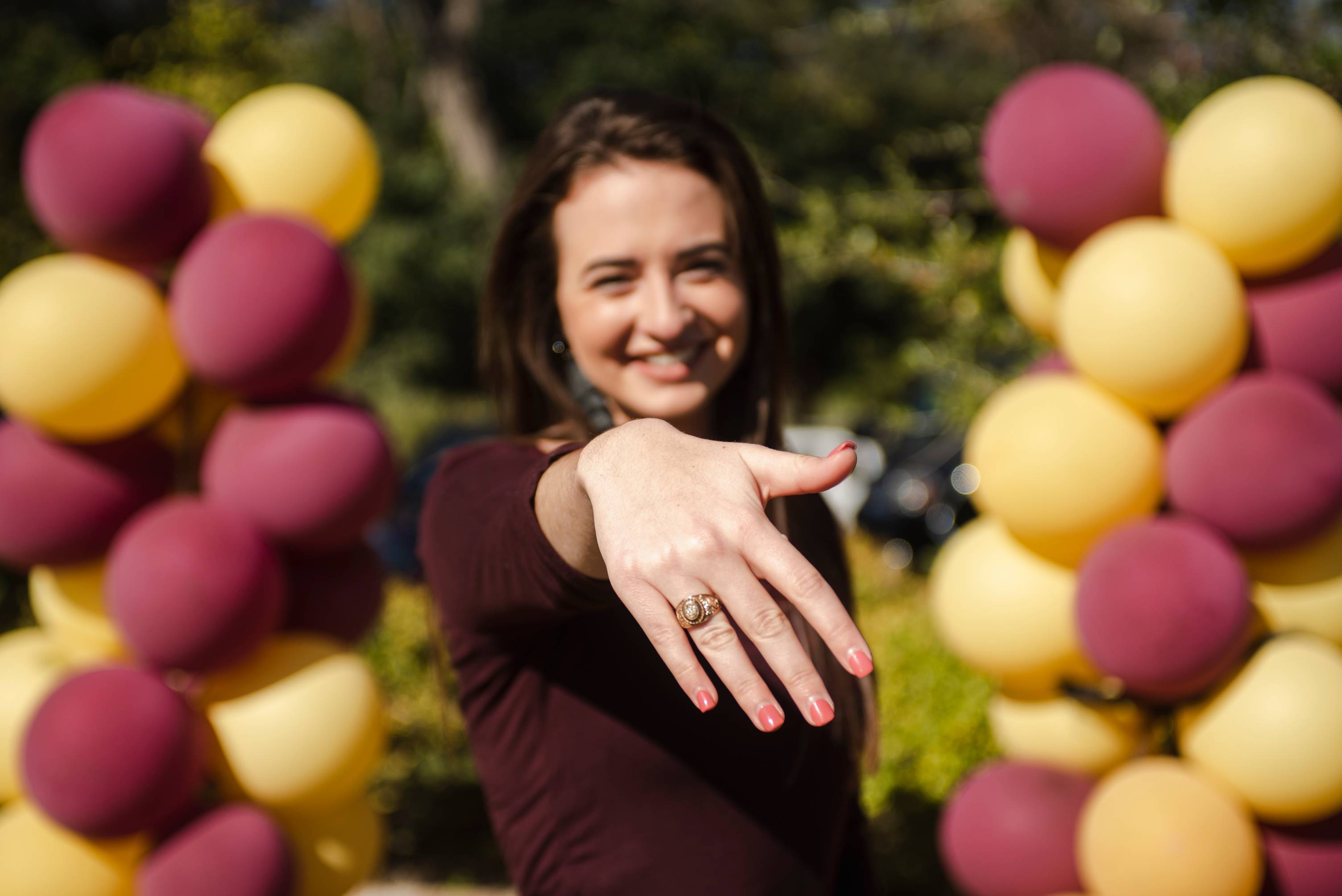 A young woman holds out her hand, displaying her TXST ring.