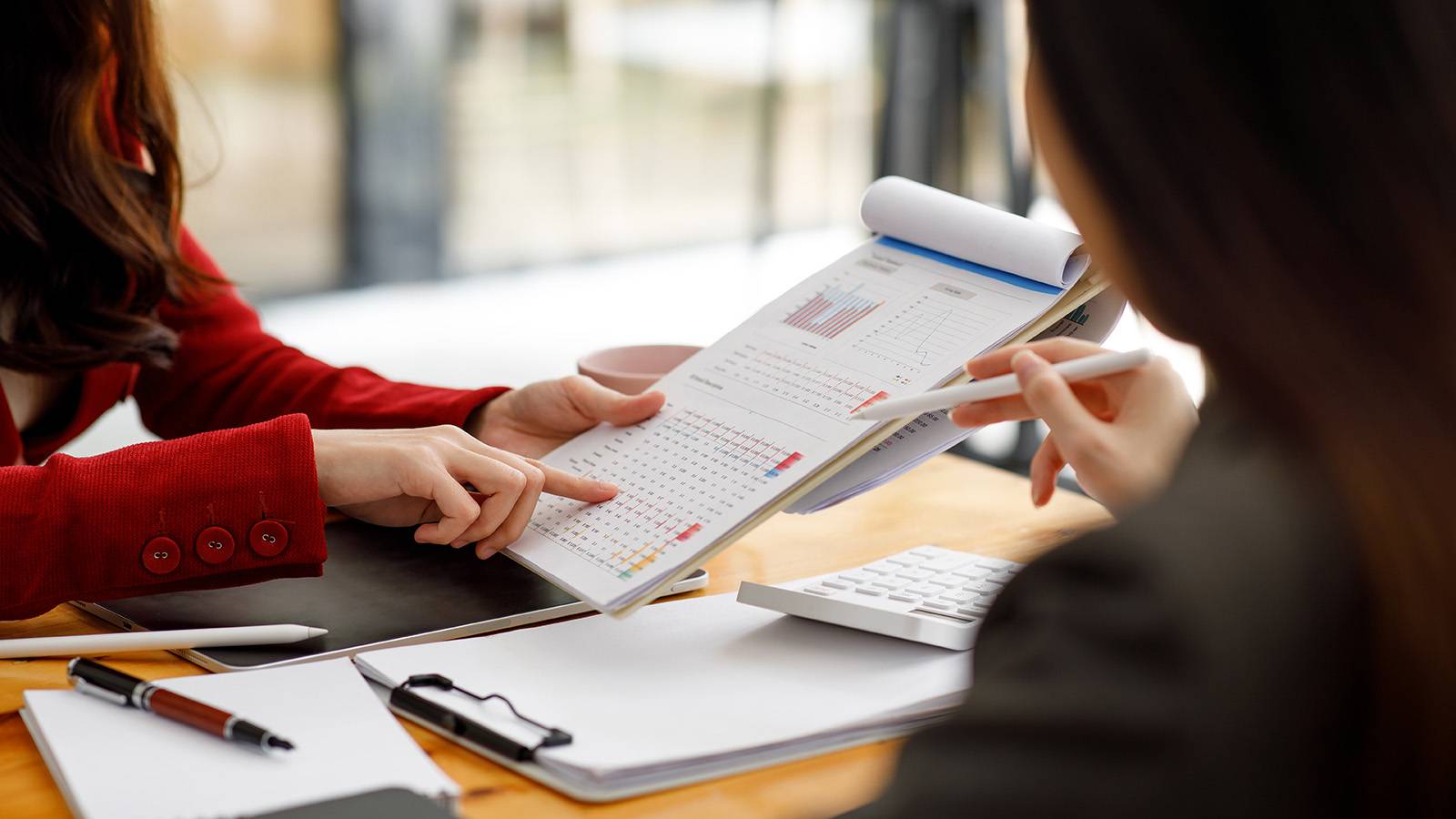 two women at a desk looking over and discussing documents